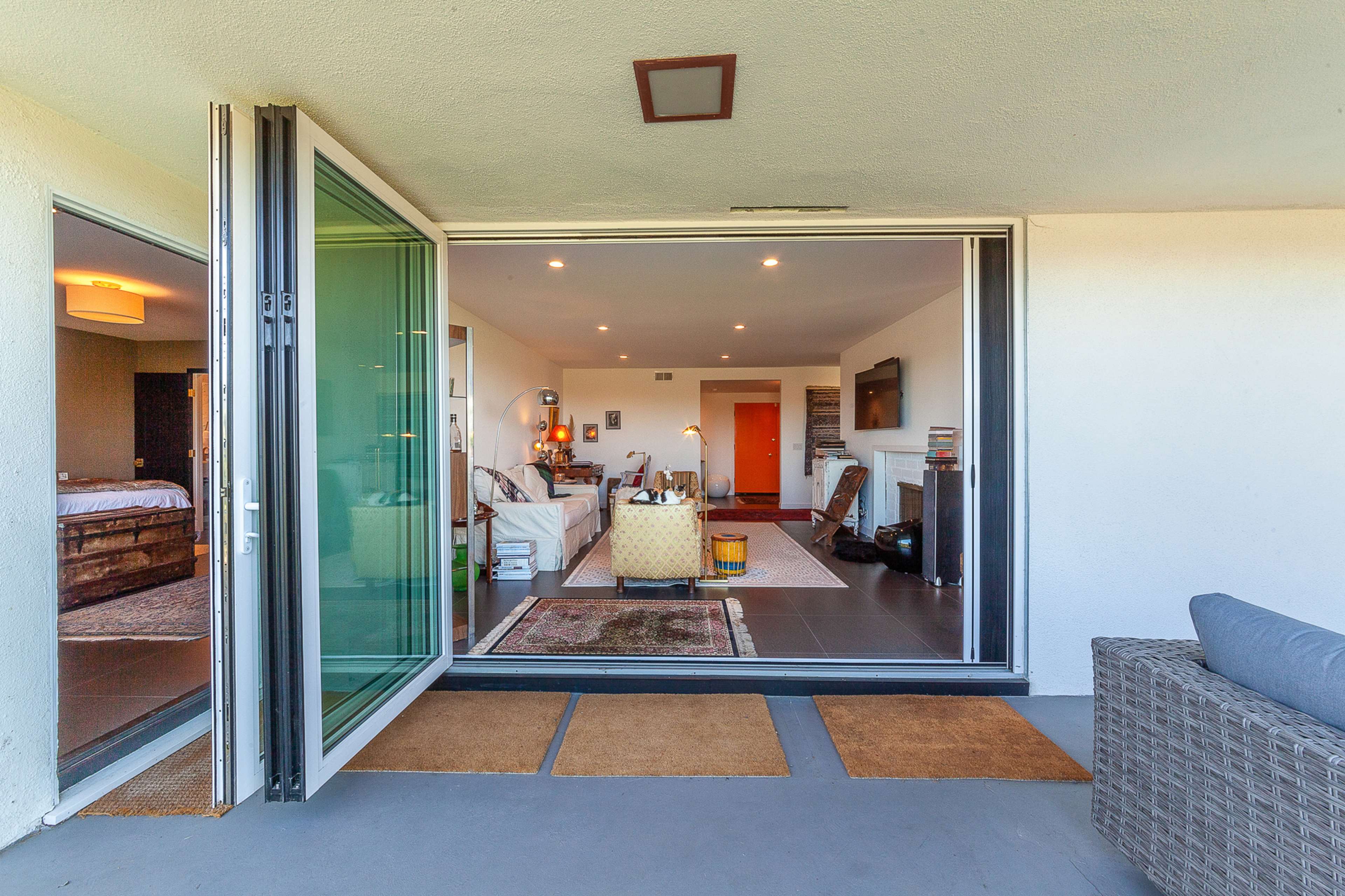 A spacious patio opens into a well-lit living area with modern furnishings and a large flat-screen TV.