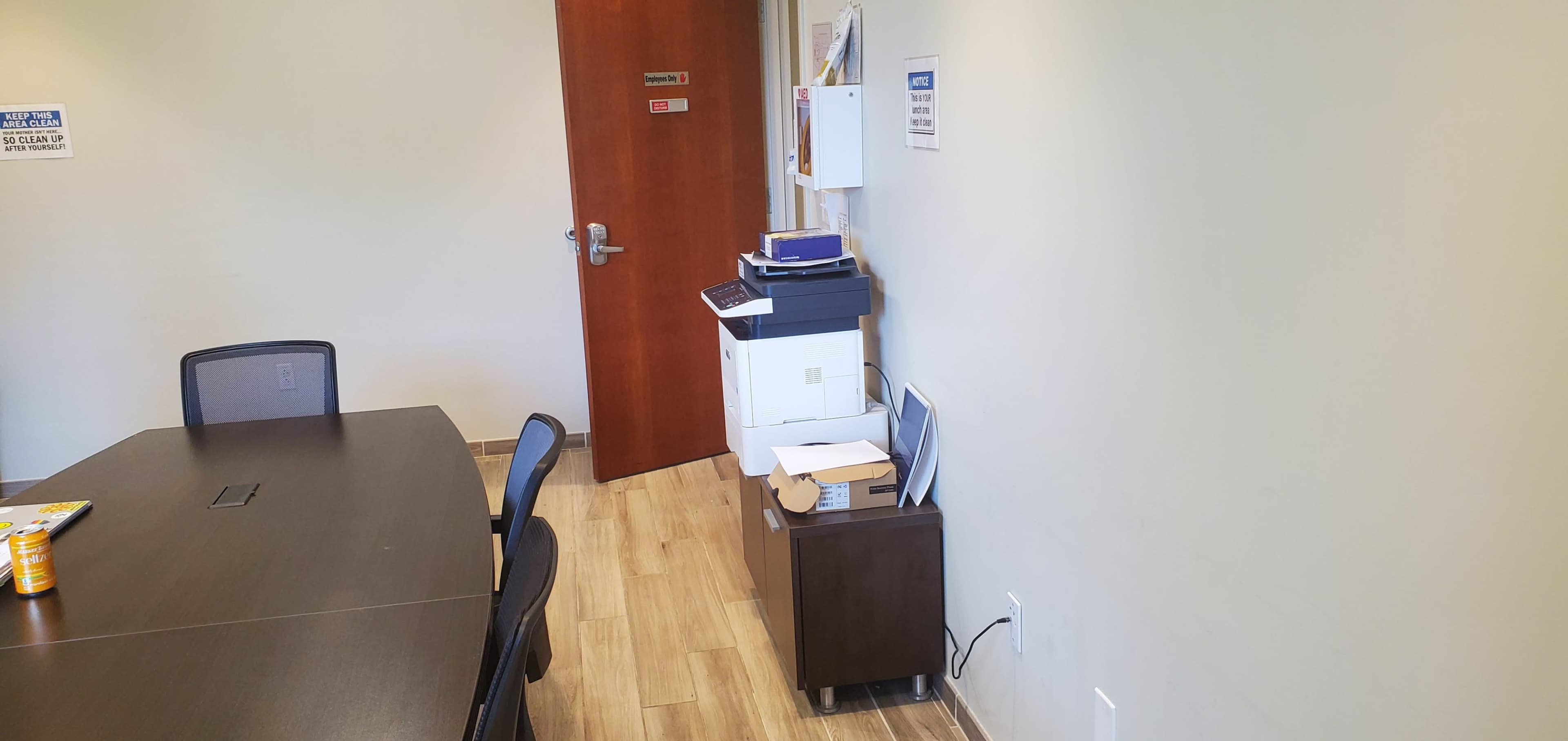 A small office space with a conference table, a printer, and a closed door in the background.