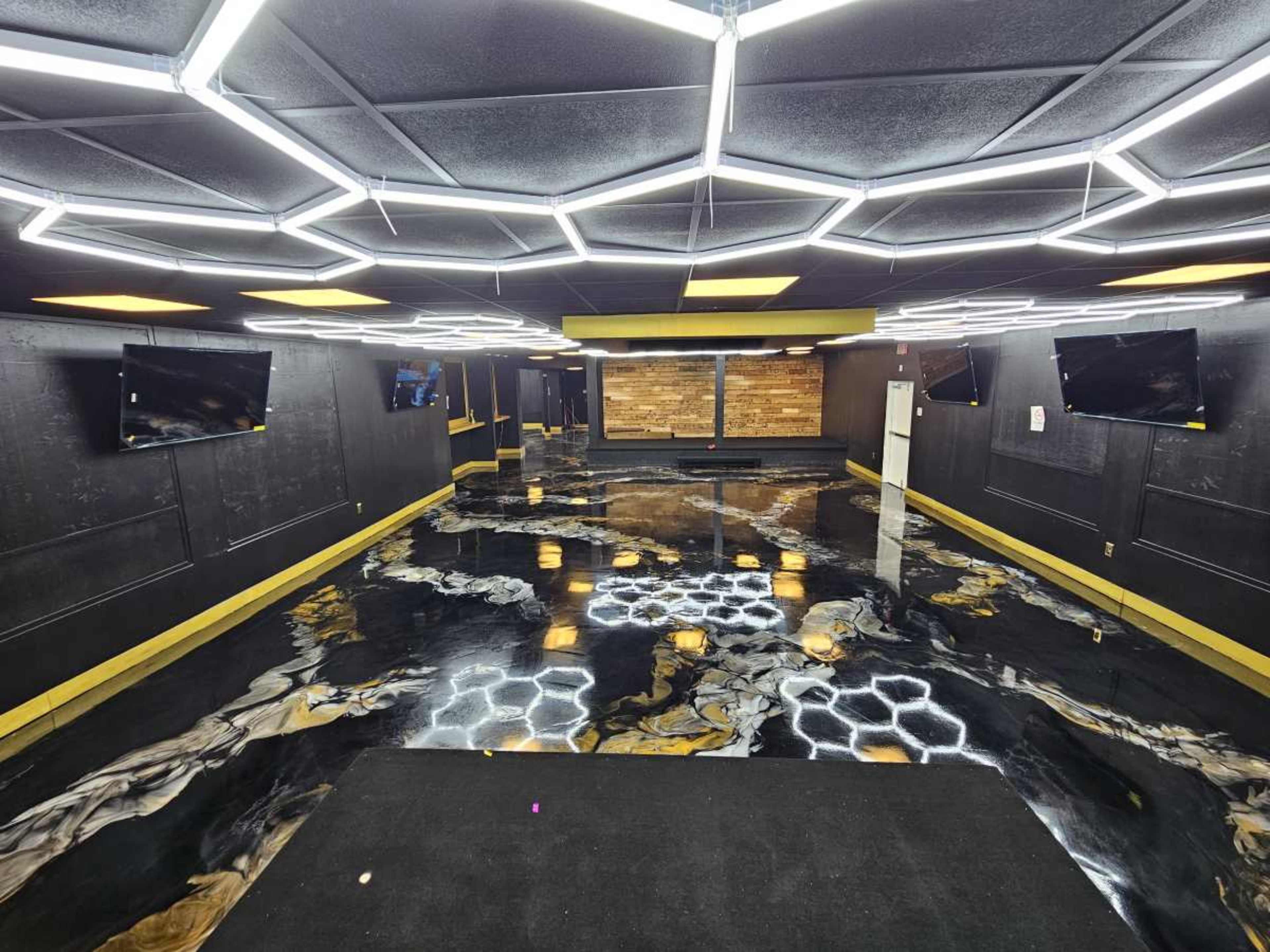 The image shows an empty room with hexagonal LED lighting on the ceiling, dark walls, and a polished floor featuring a glossy, marbled pattern.