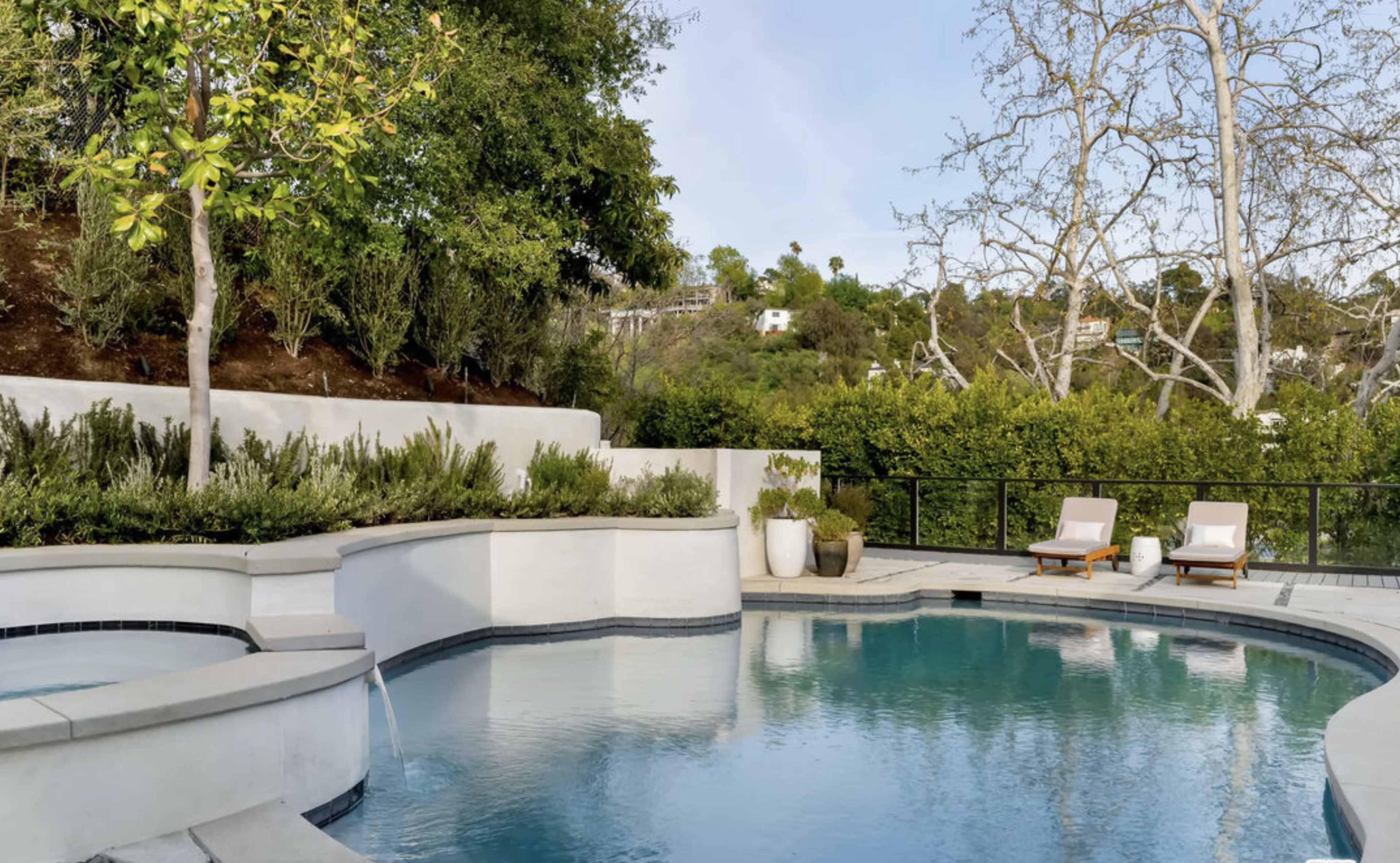 A serene swimming pool surrounded by landscaped greenery and outdoor lounge chairs.