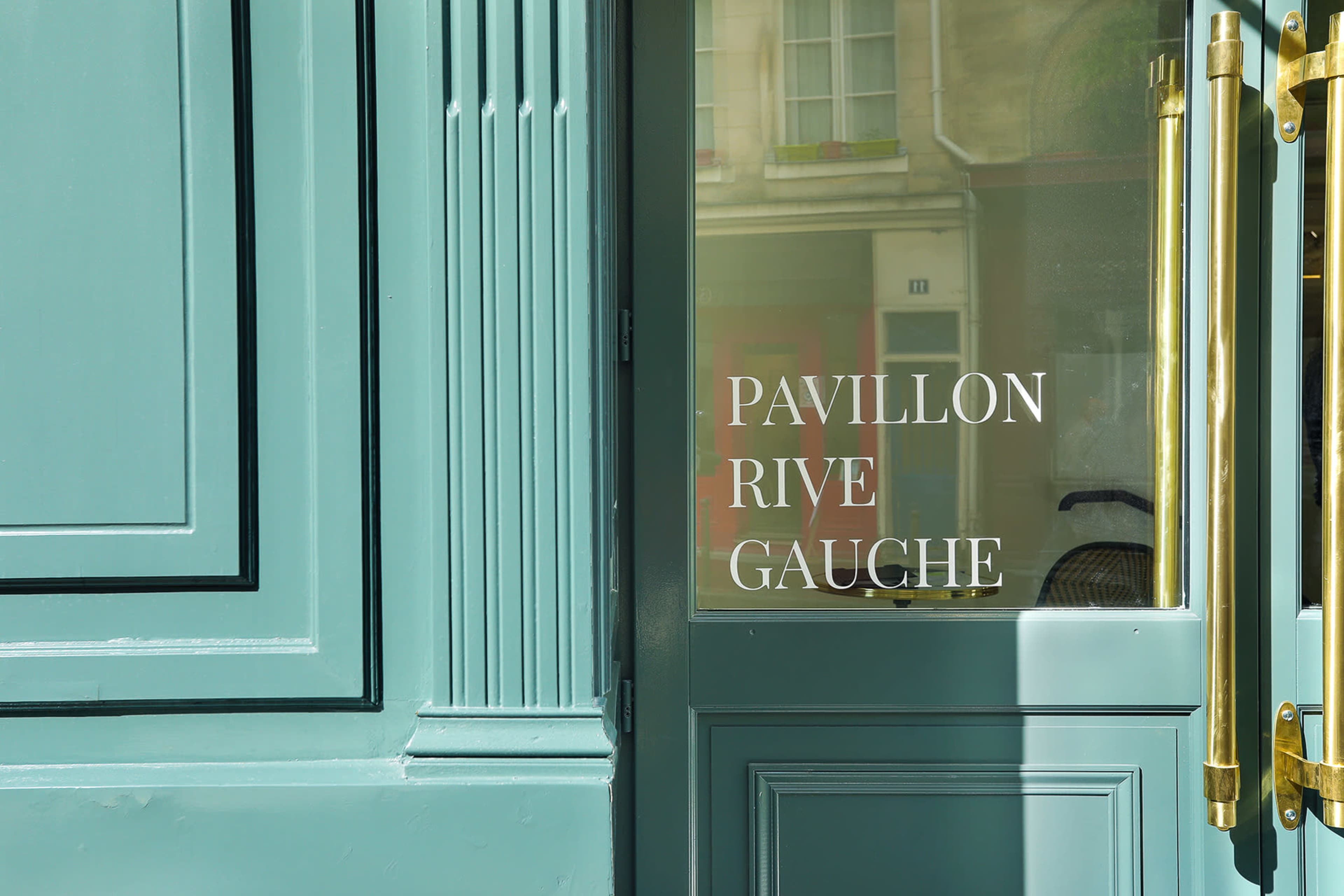 A turquoise door with a glass panel displaying the text "PAVILLON RIVE GAUCHE."