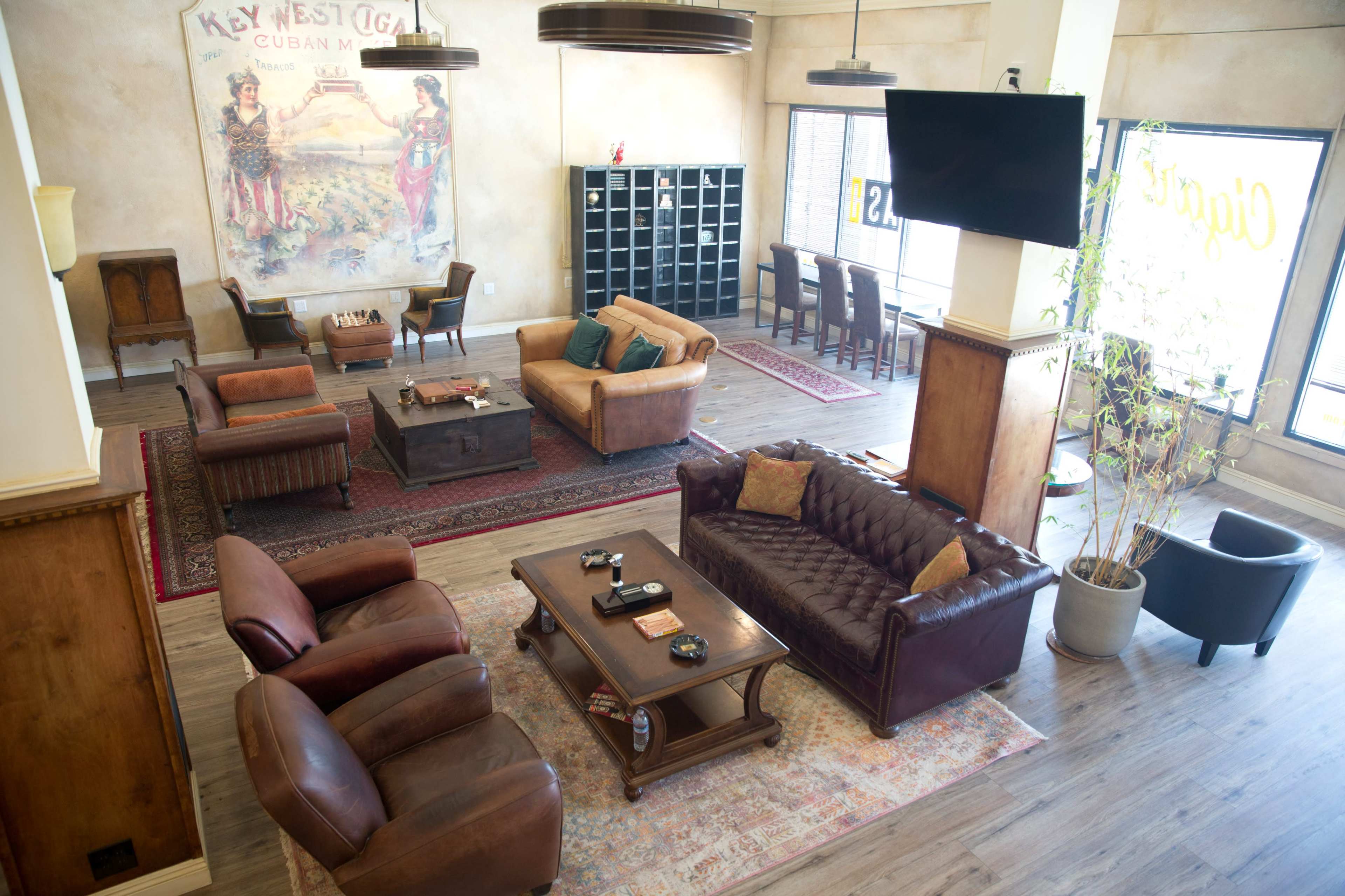 The interior of a spacious lounge features leather seating, a wooden coffee table, and a mural depicting a Cuban theme on the wall.
