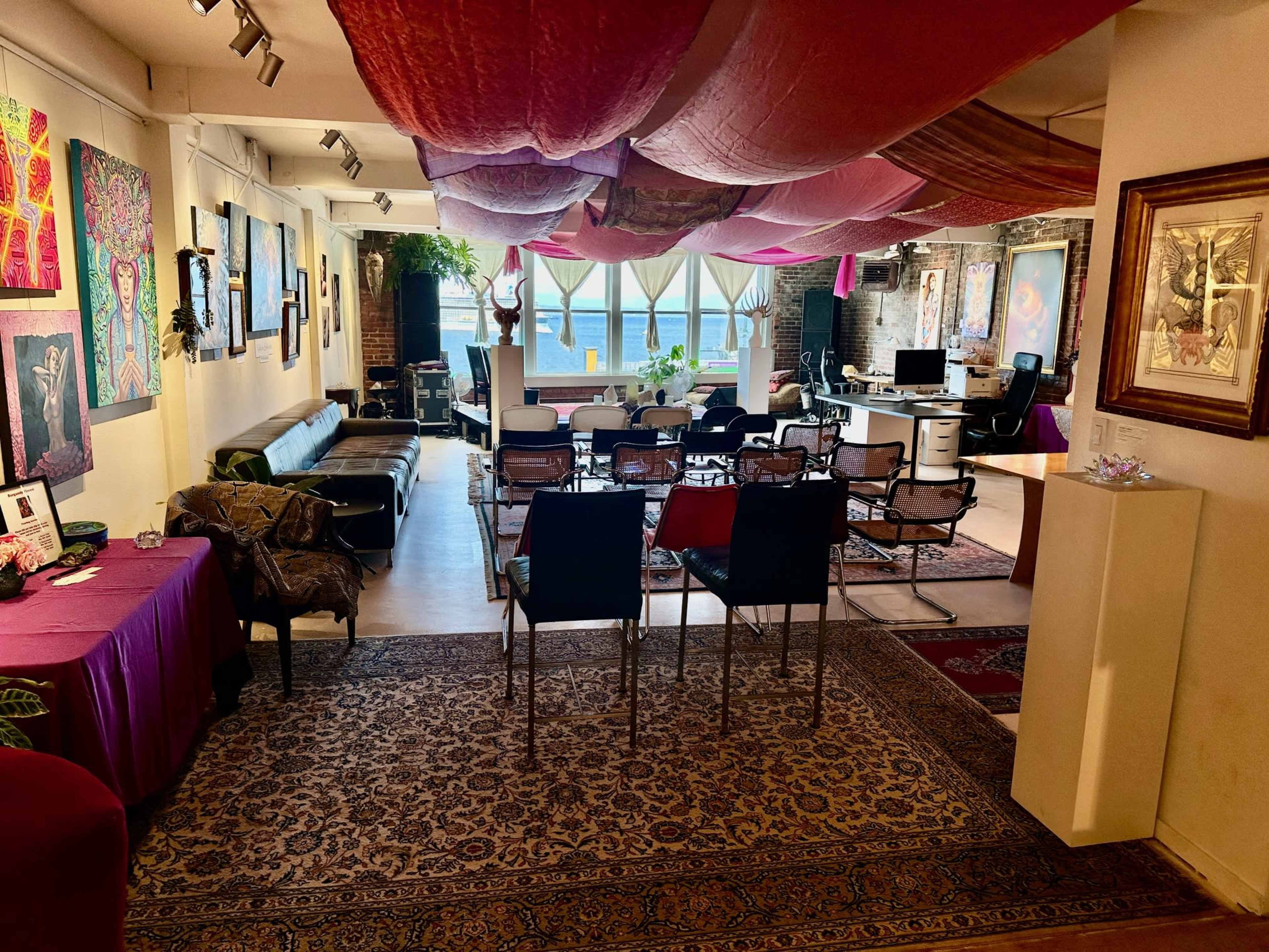 A spacious interior space decorated with artworks, featuring seating arrangements and draped fabric overhead.