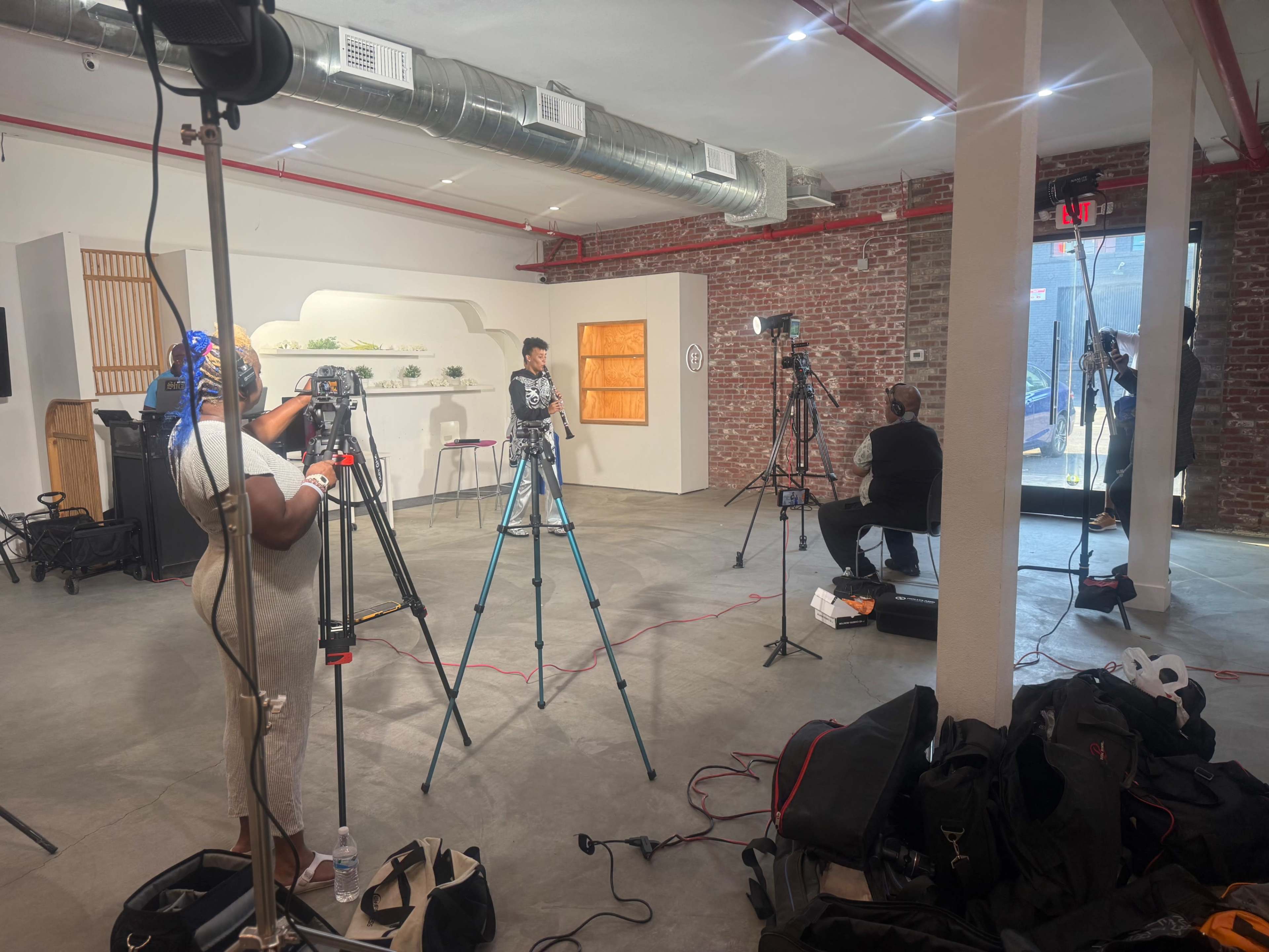 The image shows a modern studio setup with several cameras and lighting equipment focused on a seated person, while another individual is positioned off to the side.