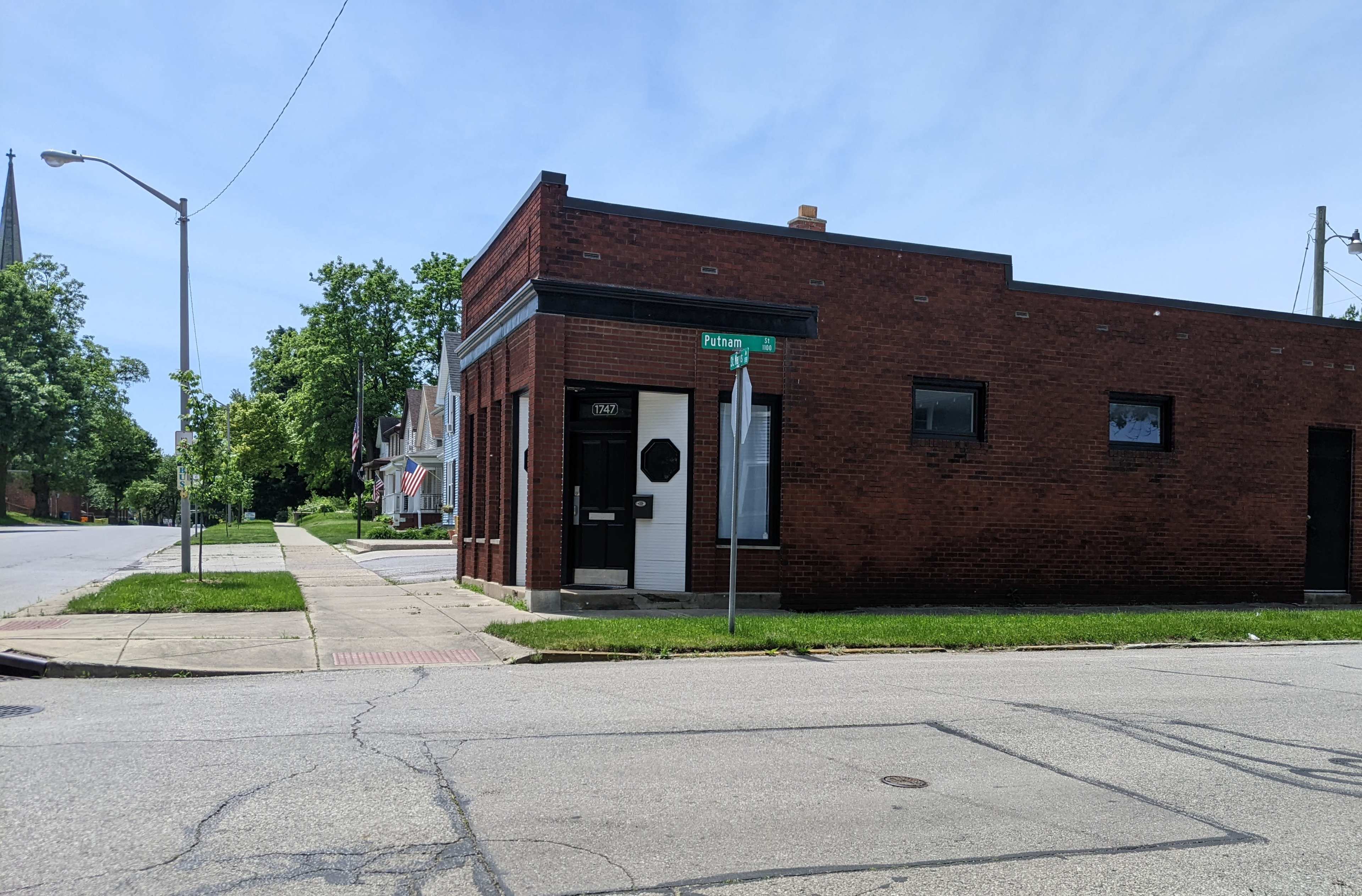A brick building located on the corner of a street, with a stop sign and a lamppost nearby.