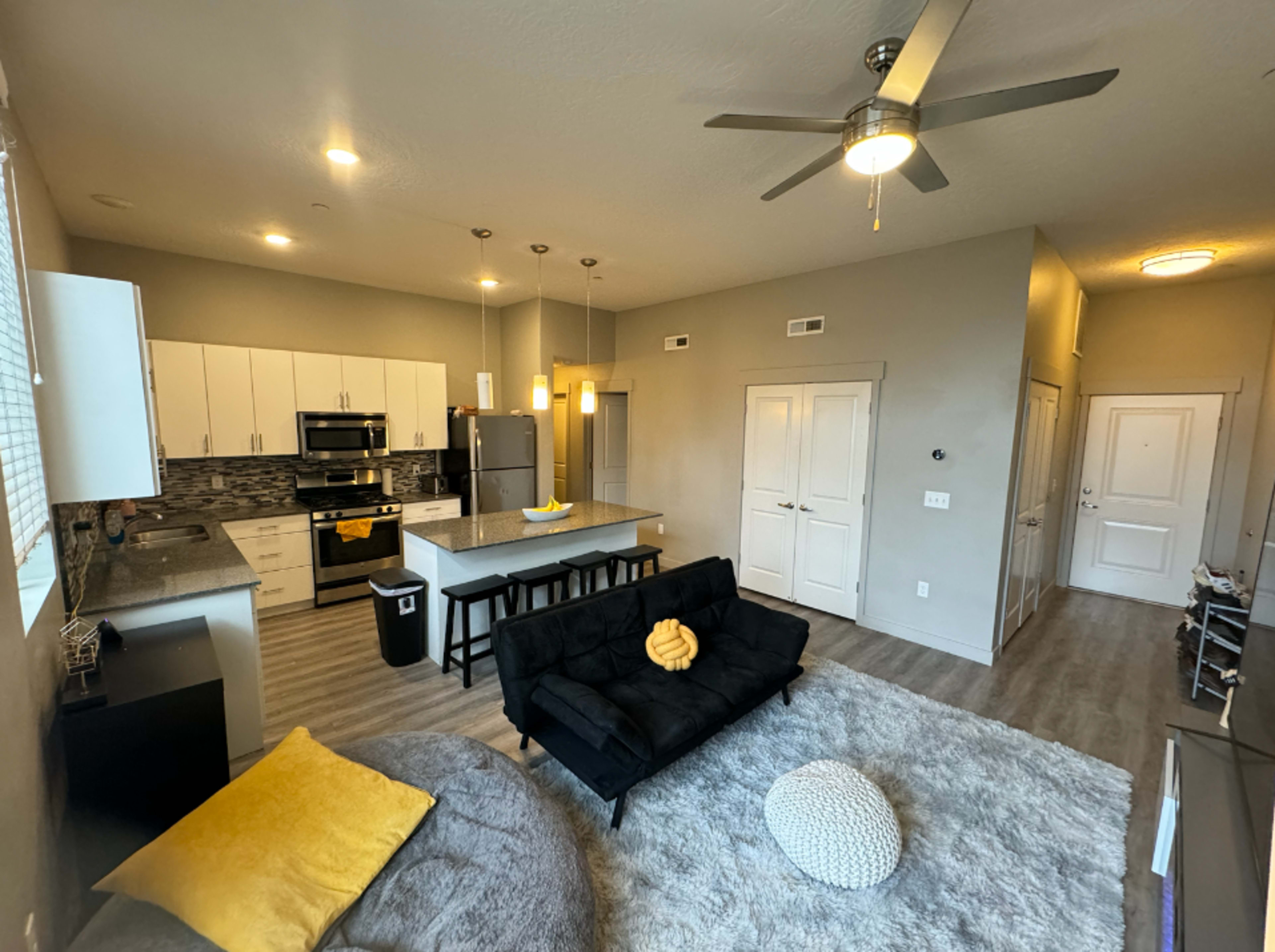 A modern, open-concept living area featuring a kitchen with sleek cabinets, a dining island, and a cozy seating arrangement.