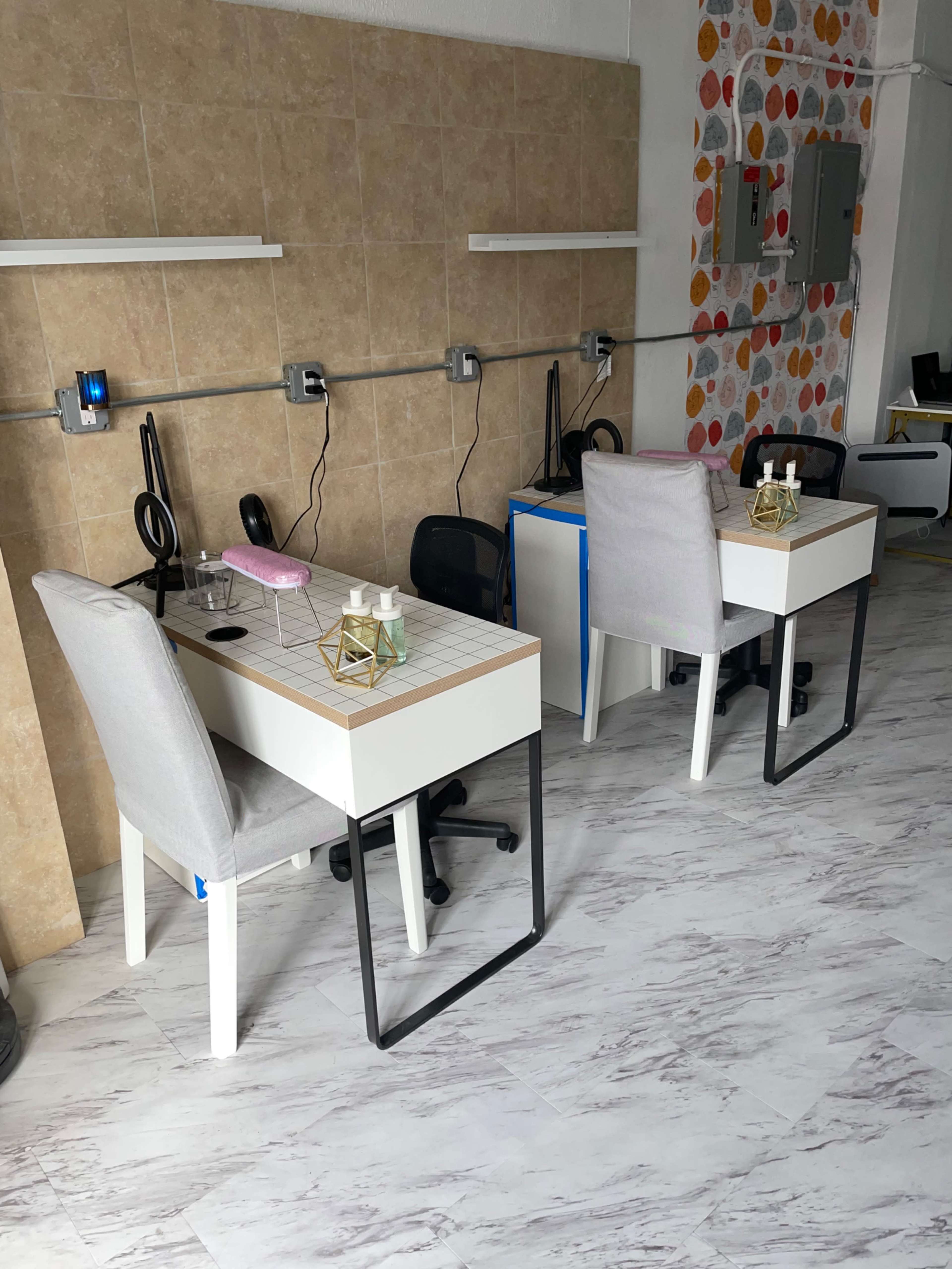 The image shows two workstations with white desks and chairs, situated in a room with tiled walls and patterned decorations.