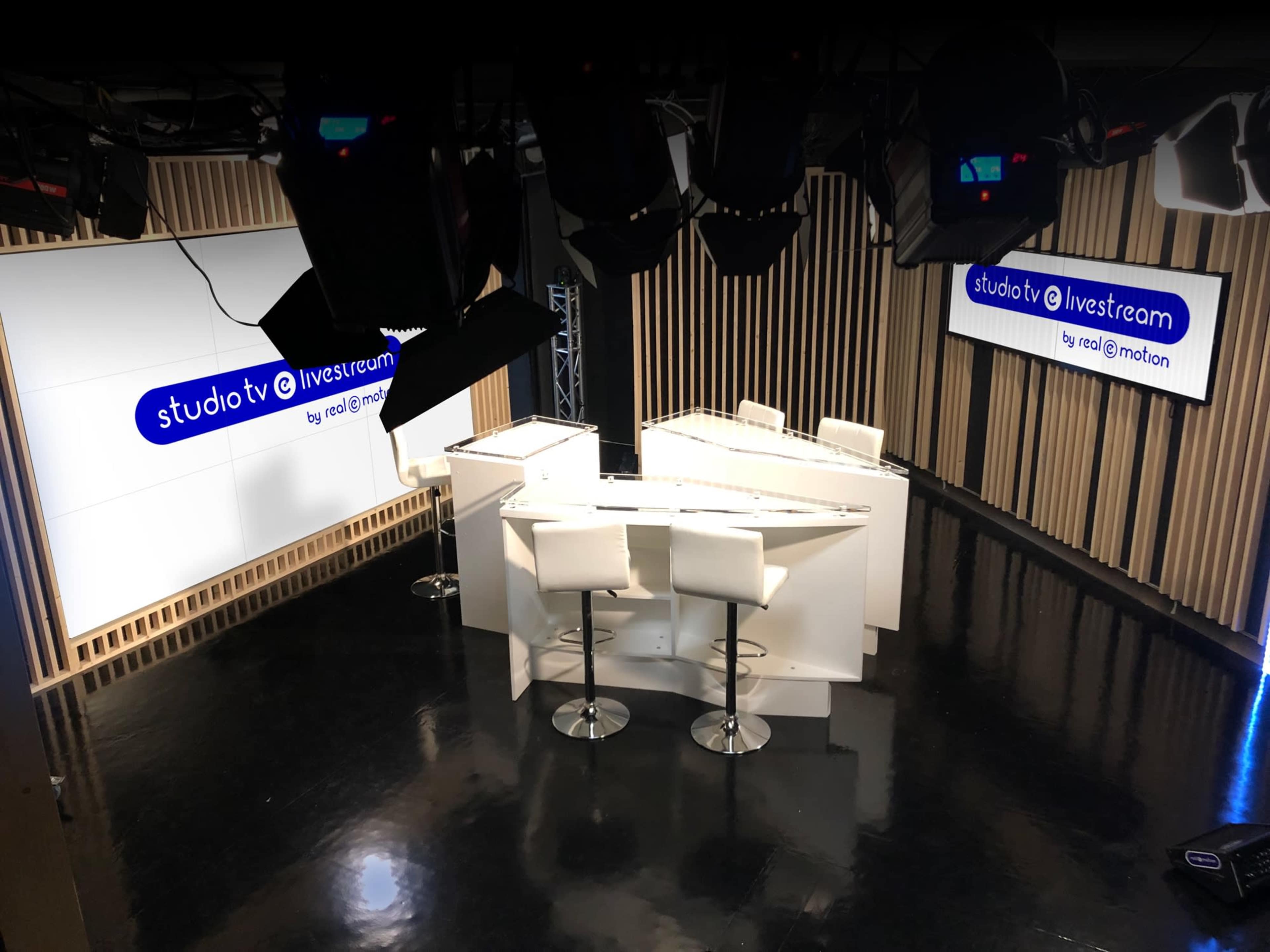 A modern studio setup with white furniture and large screens displaying the text "studiotv @ livestream."