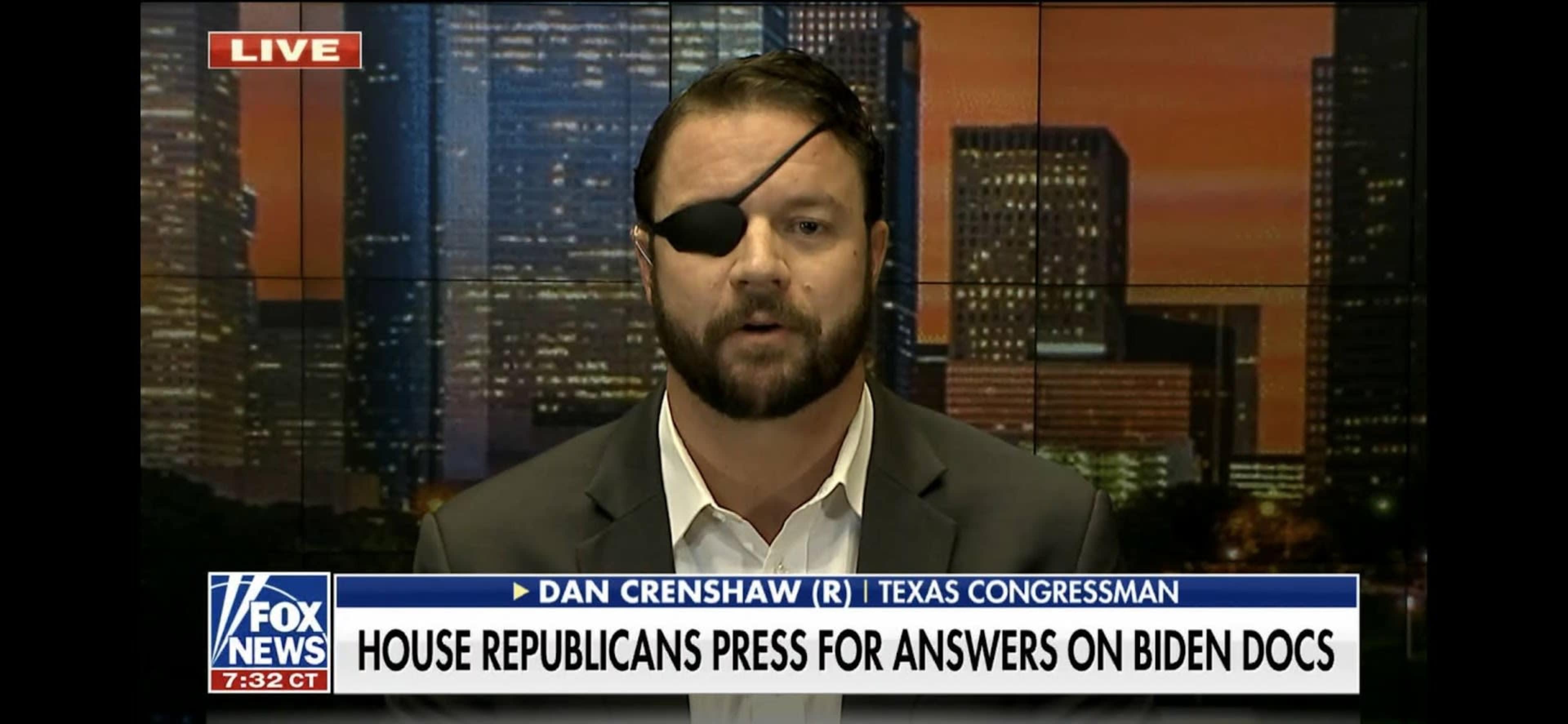 A man wearing an eye patch speaks on a news program set against a backdrop of a city skyline.
