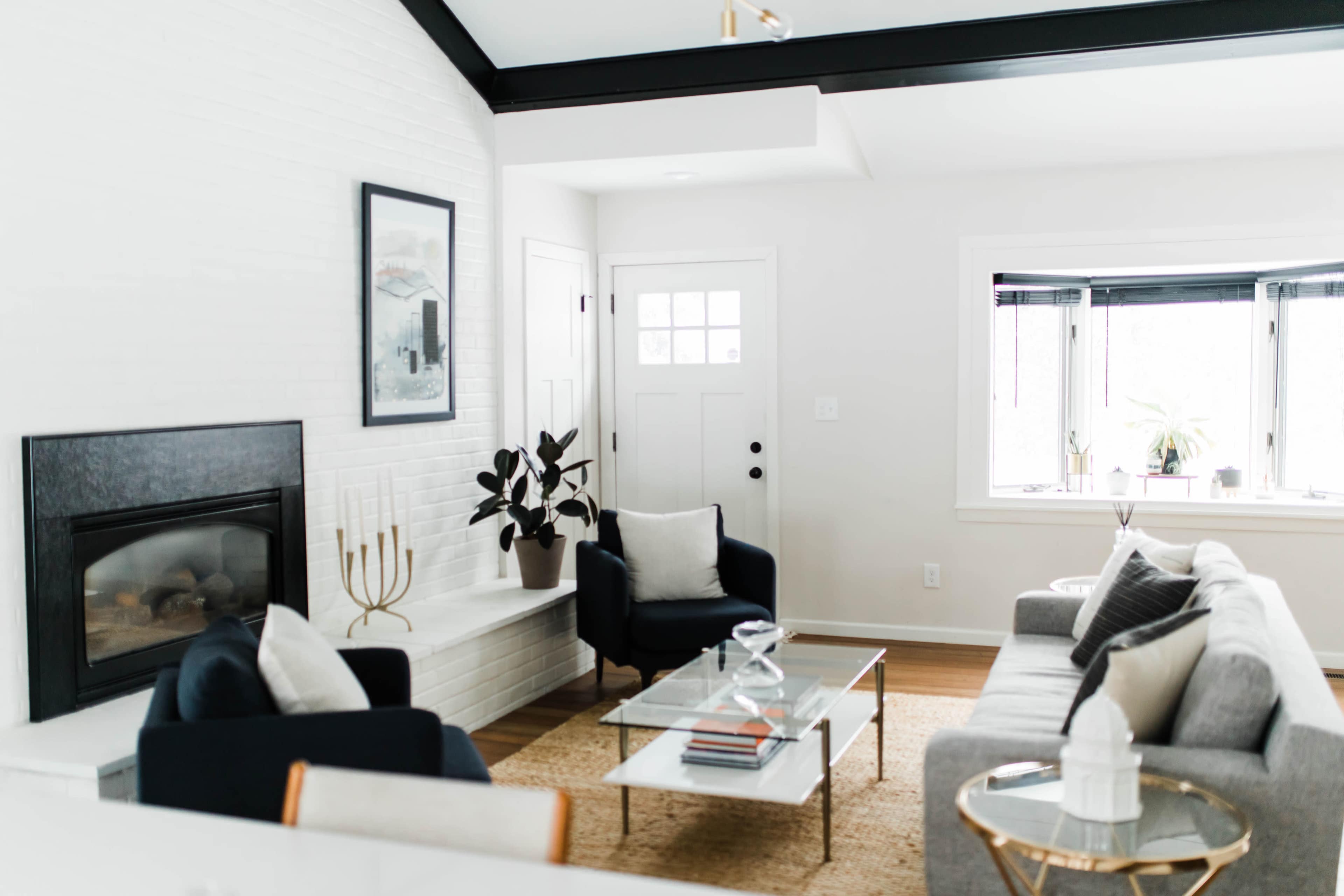 A modern living room with a fireplace, a coffee table, and a seating arrangement near large windows.