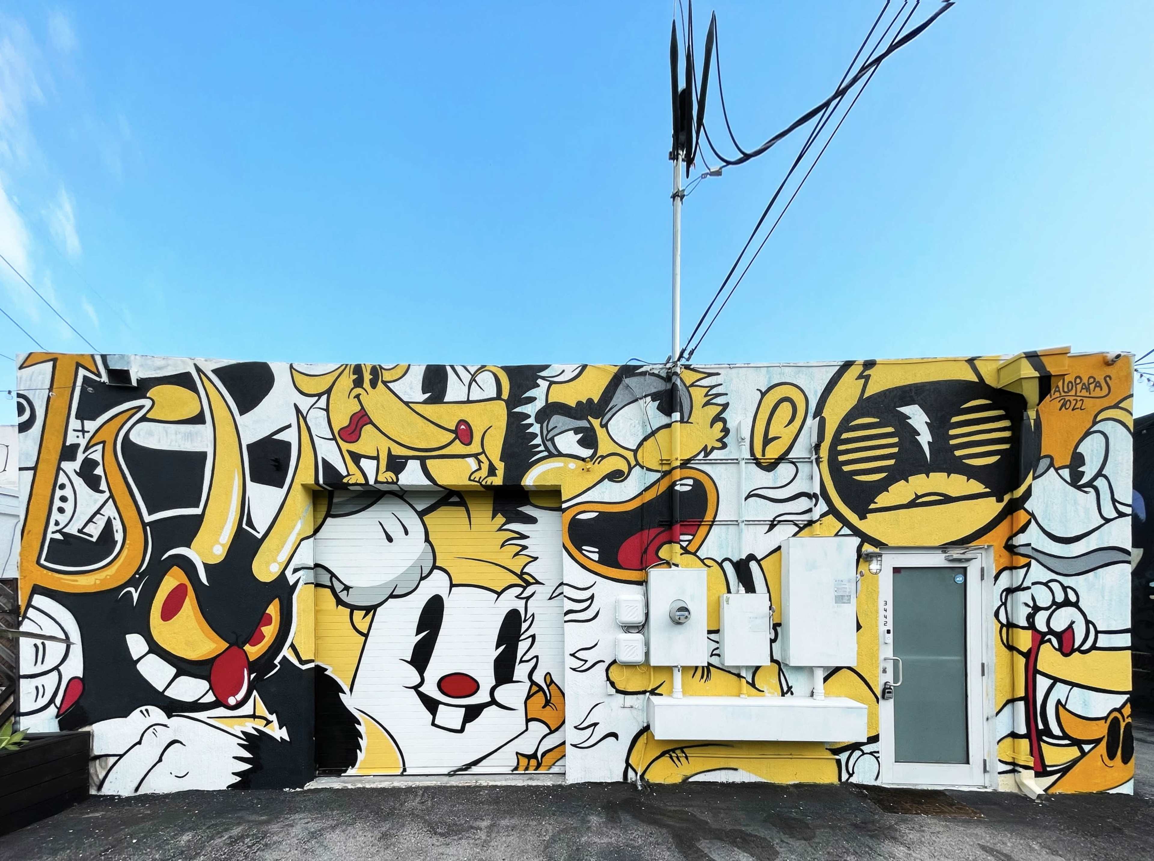 A colorful mural on a brick wall, displaying various cartoon characters in shades of yellow, black, and white.