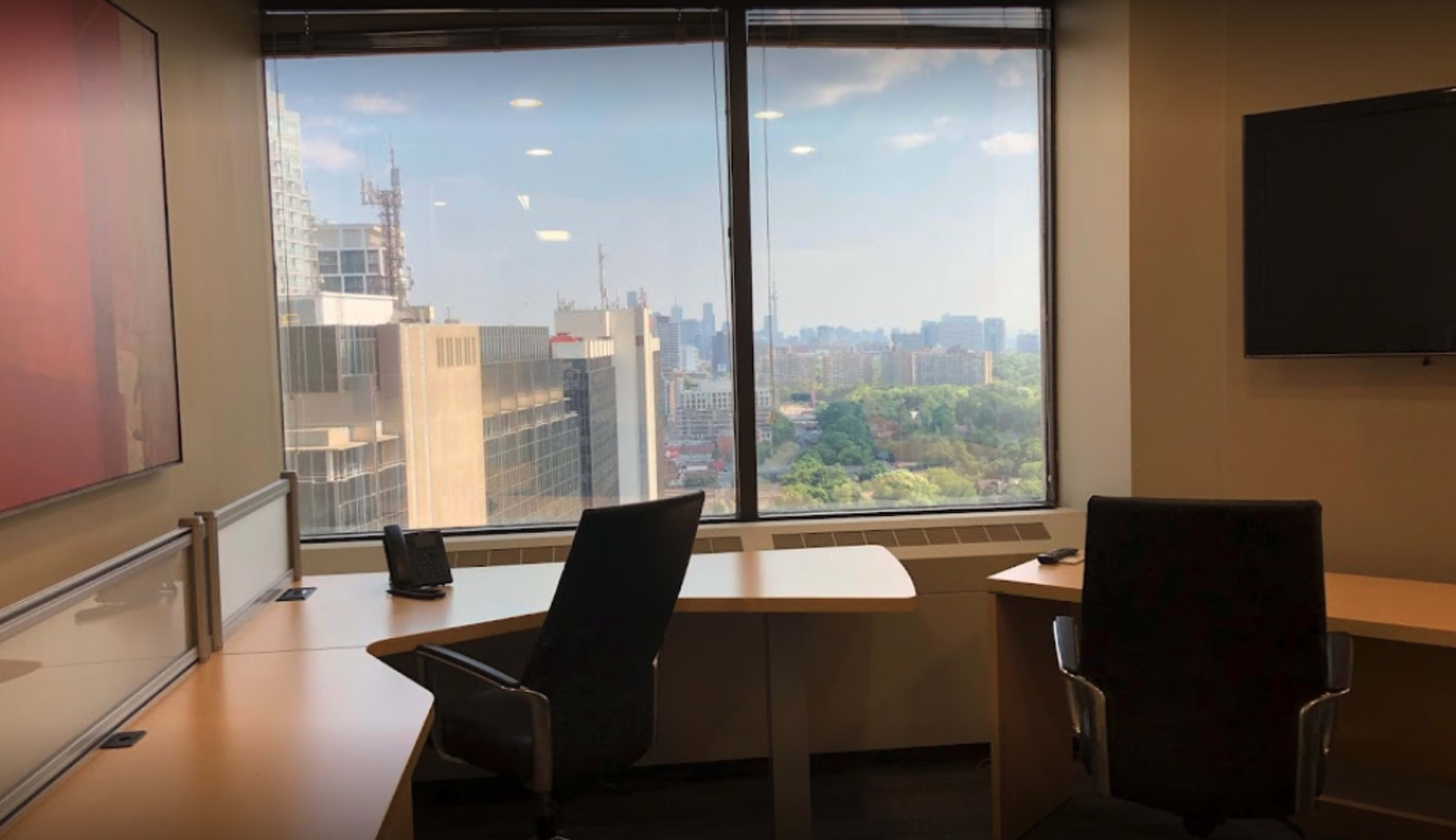 A modern office space with two empty chairs and a large window overlooking a cityscape.