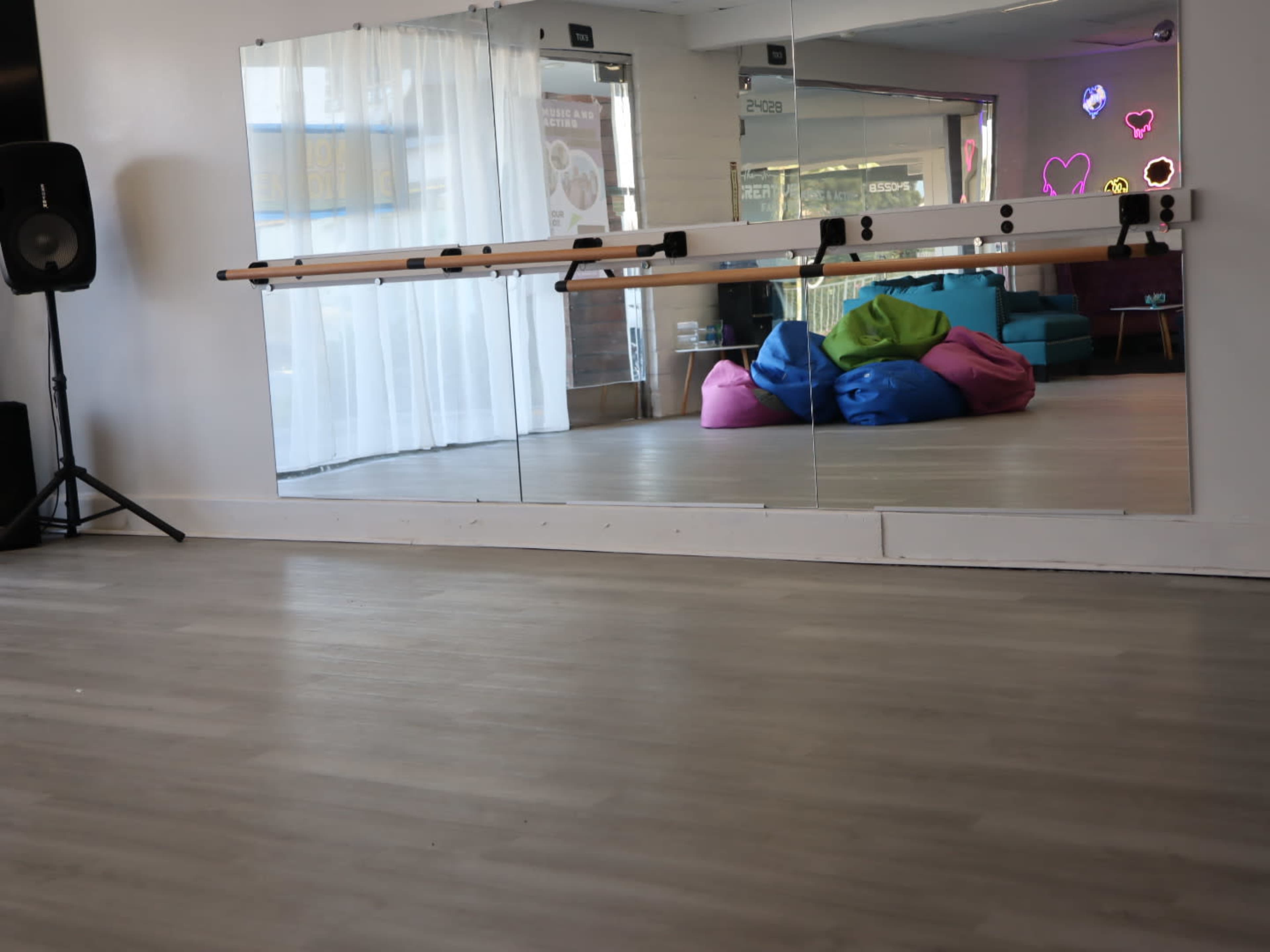 The image shows a spacious room with a mirror wall, a sound system speaker, and colorful bean bags arranged near a seating area.