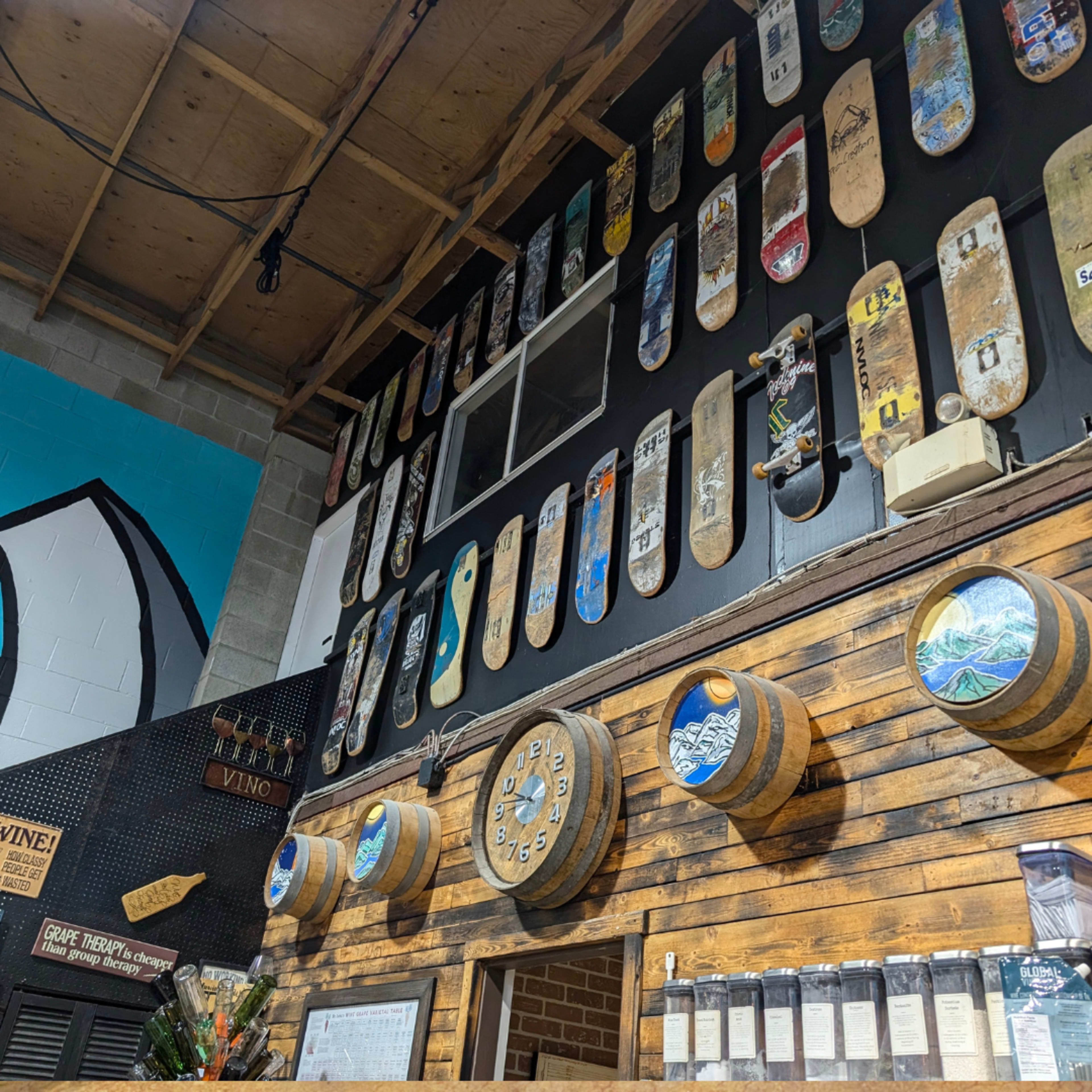The image shows a wall decorated with various vintage skateboards and wooden barrels in a rustic interior.