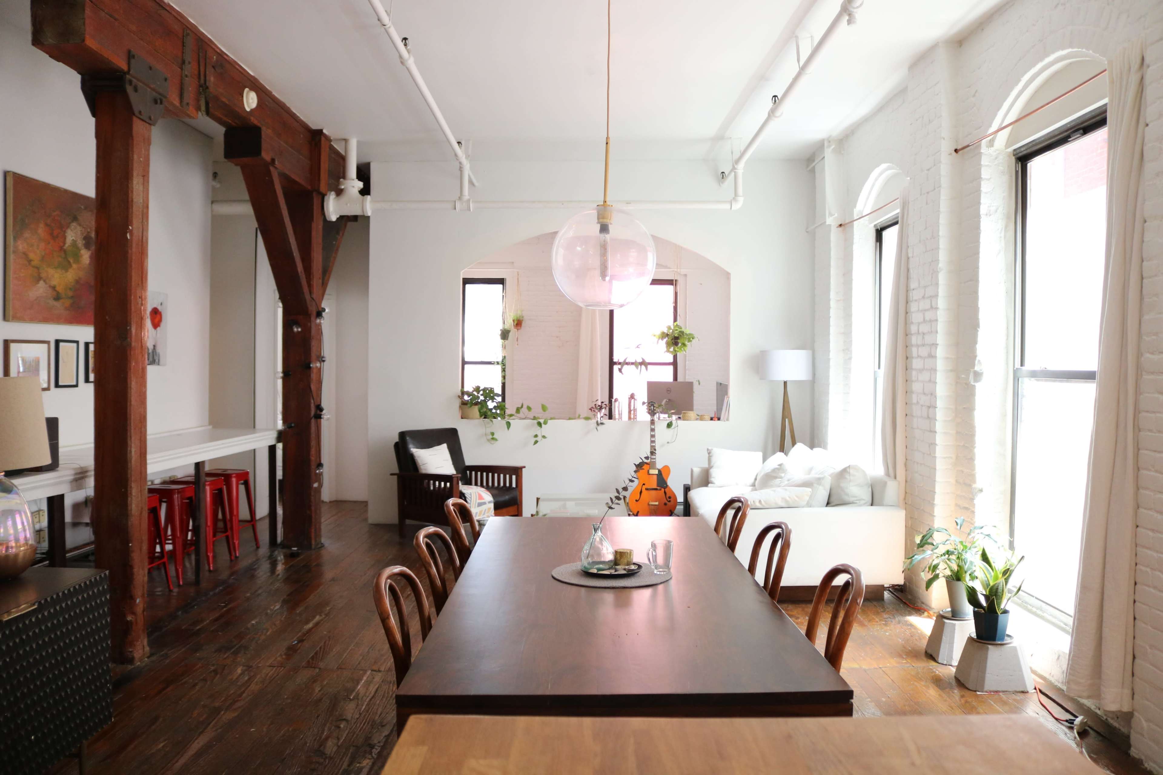 A spacious dining area features a large wooden table surrounded by chairs, with a cozy living room visible in the background.