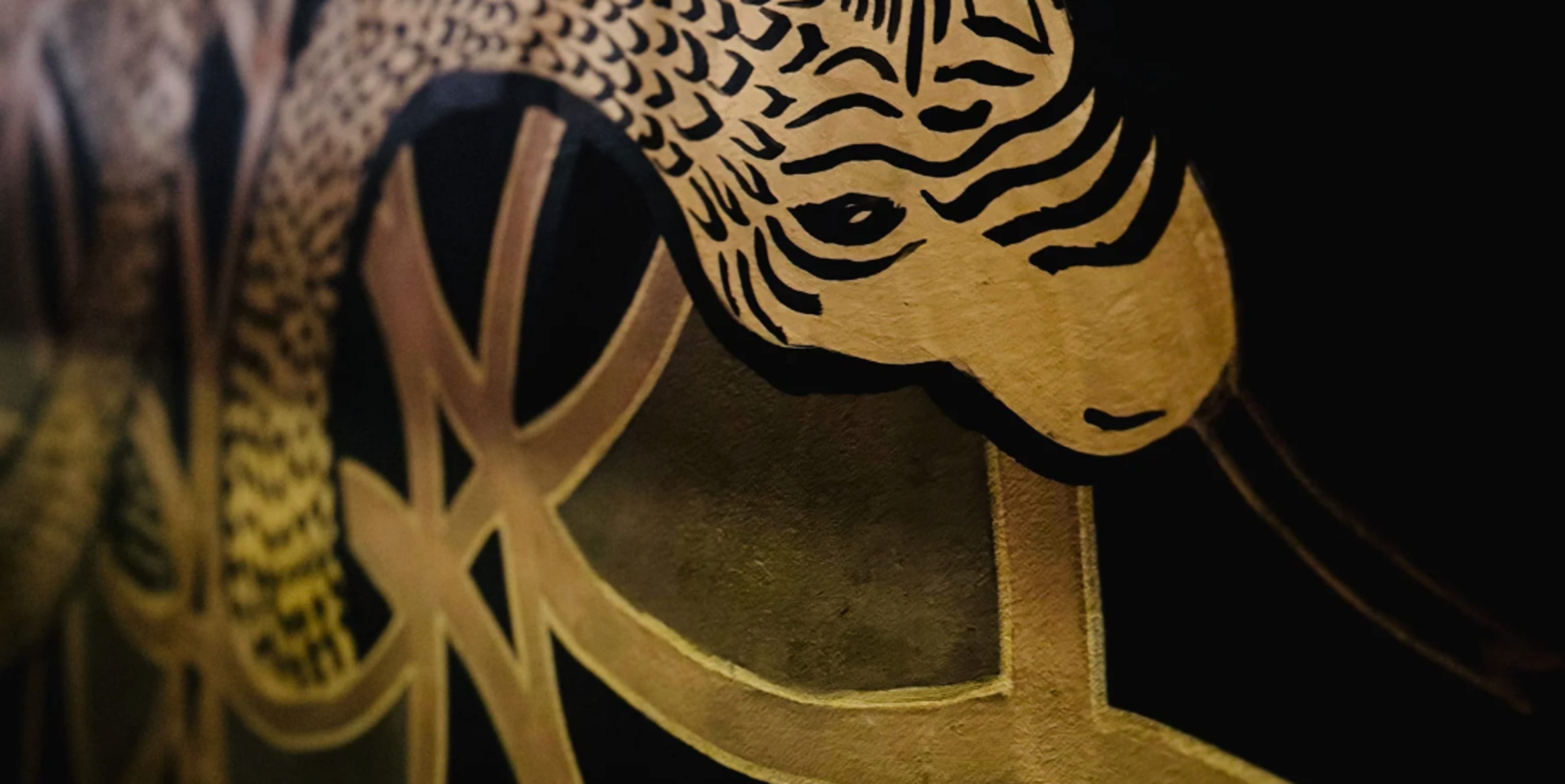 The image features a close-up of a stylized, golden snake against a dark background with geometric patterns.