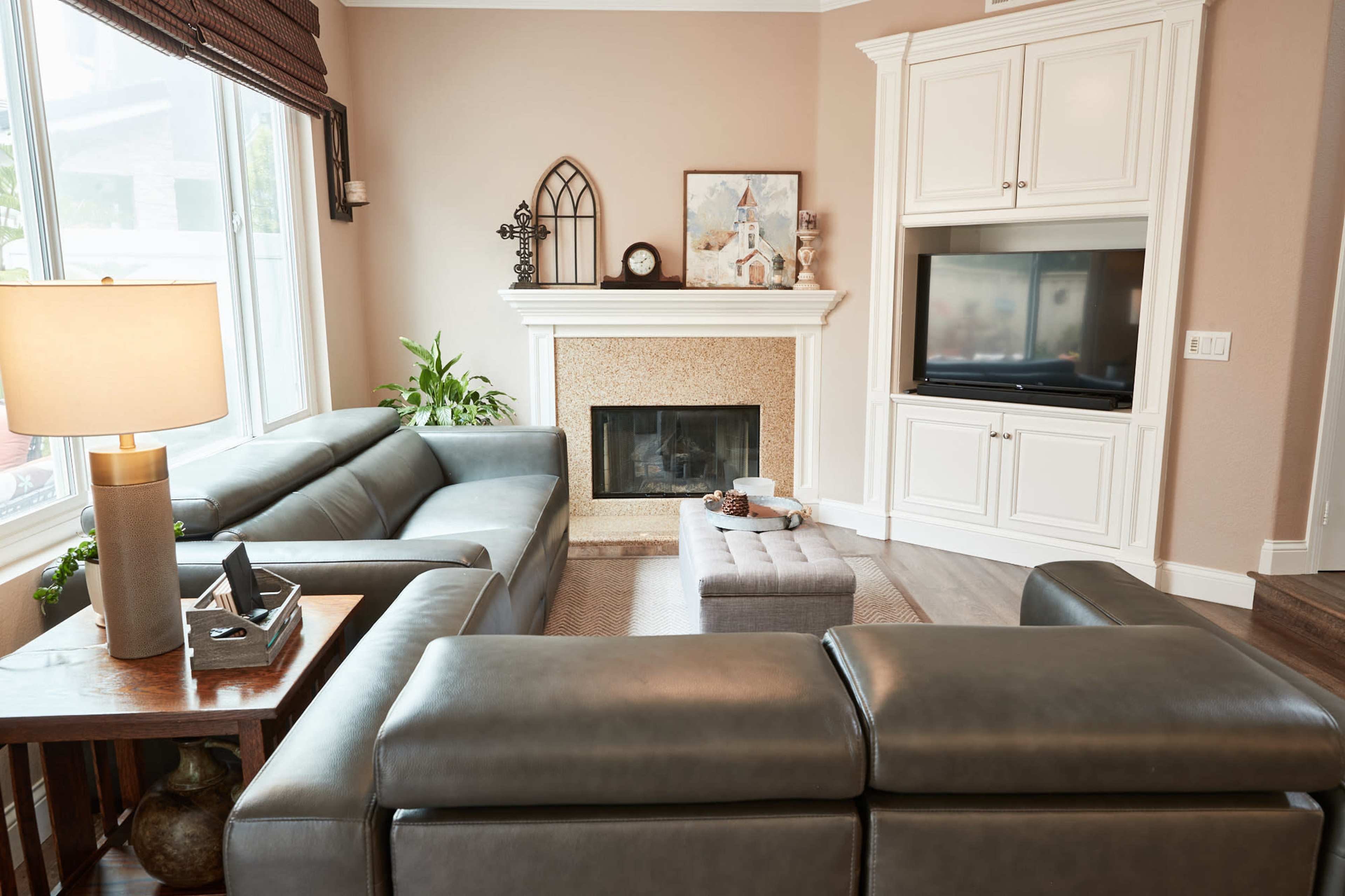 A modern living room features a large sectional sofa, a decorative fireplace, a built-in TV unit, and a coffee table in a cozy arrangement.