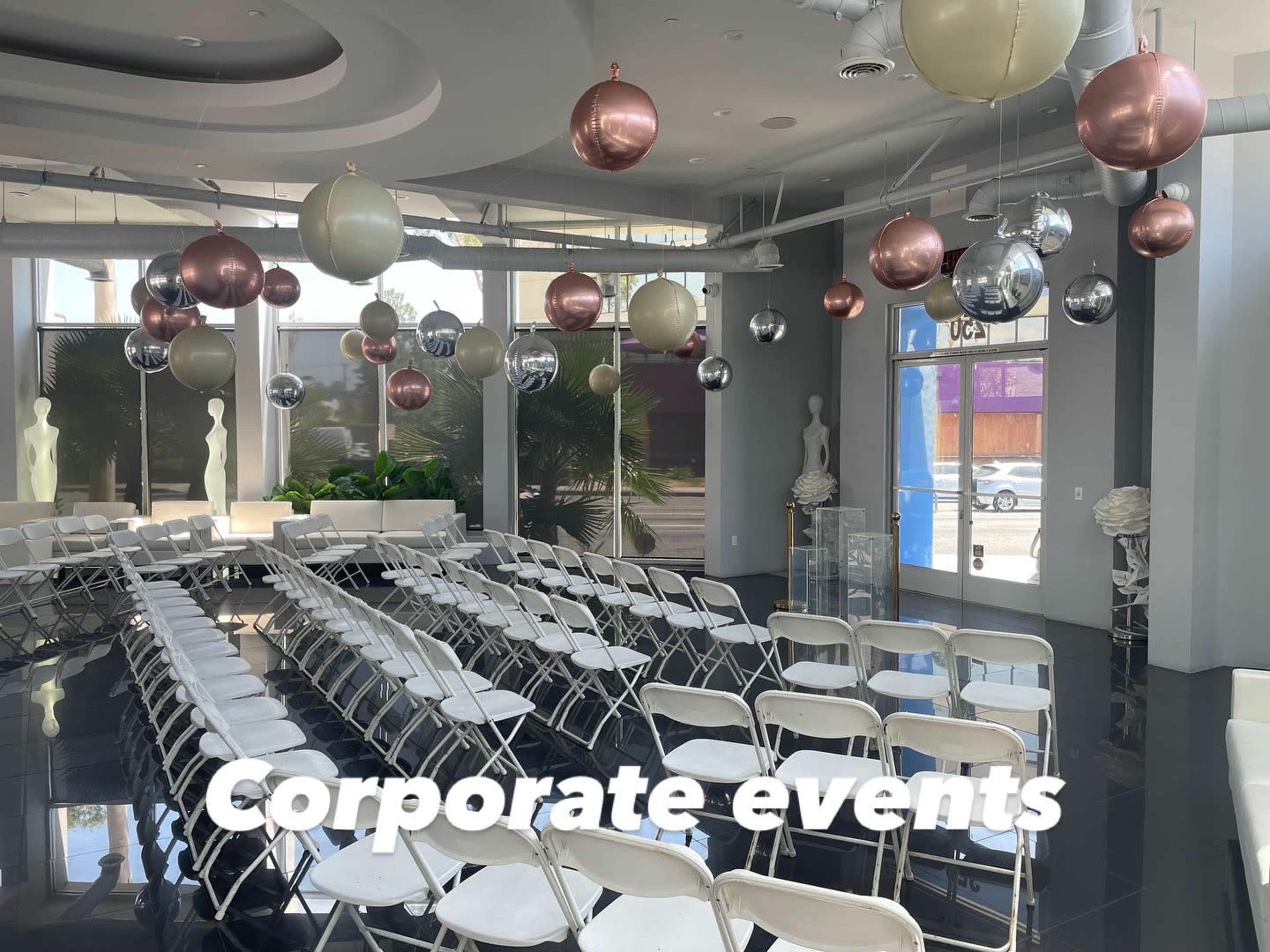 A spacious room set up with white folding chairs arranged in rows, adorned with large decorative balloons hanging from the ceiling.
