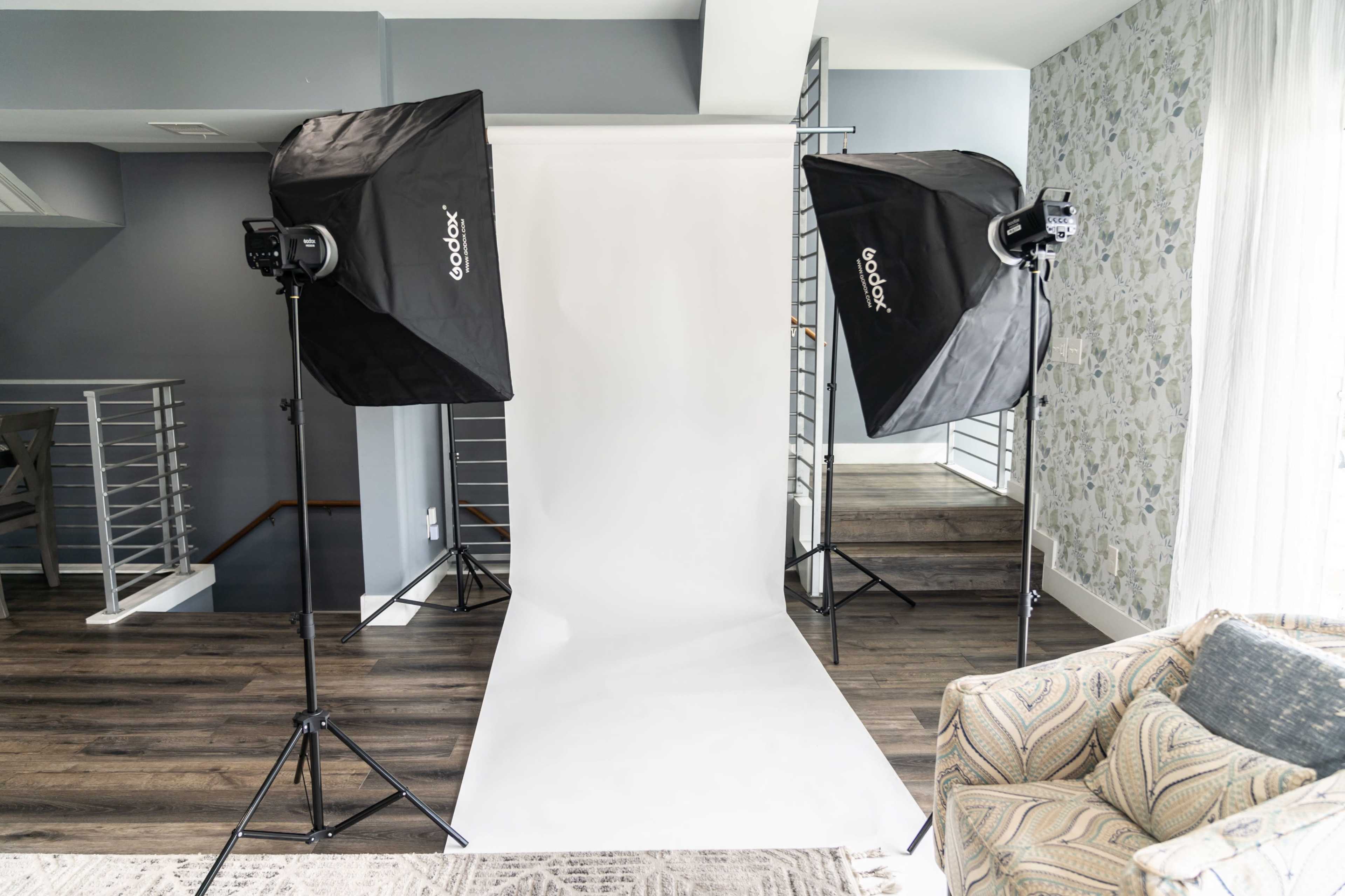 A photography setup with two softbox lights flanking a white backdrop in a well-lit room.