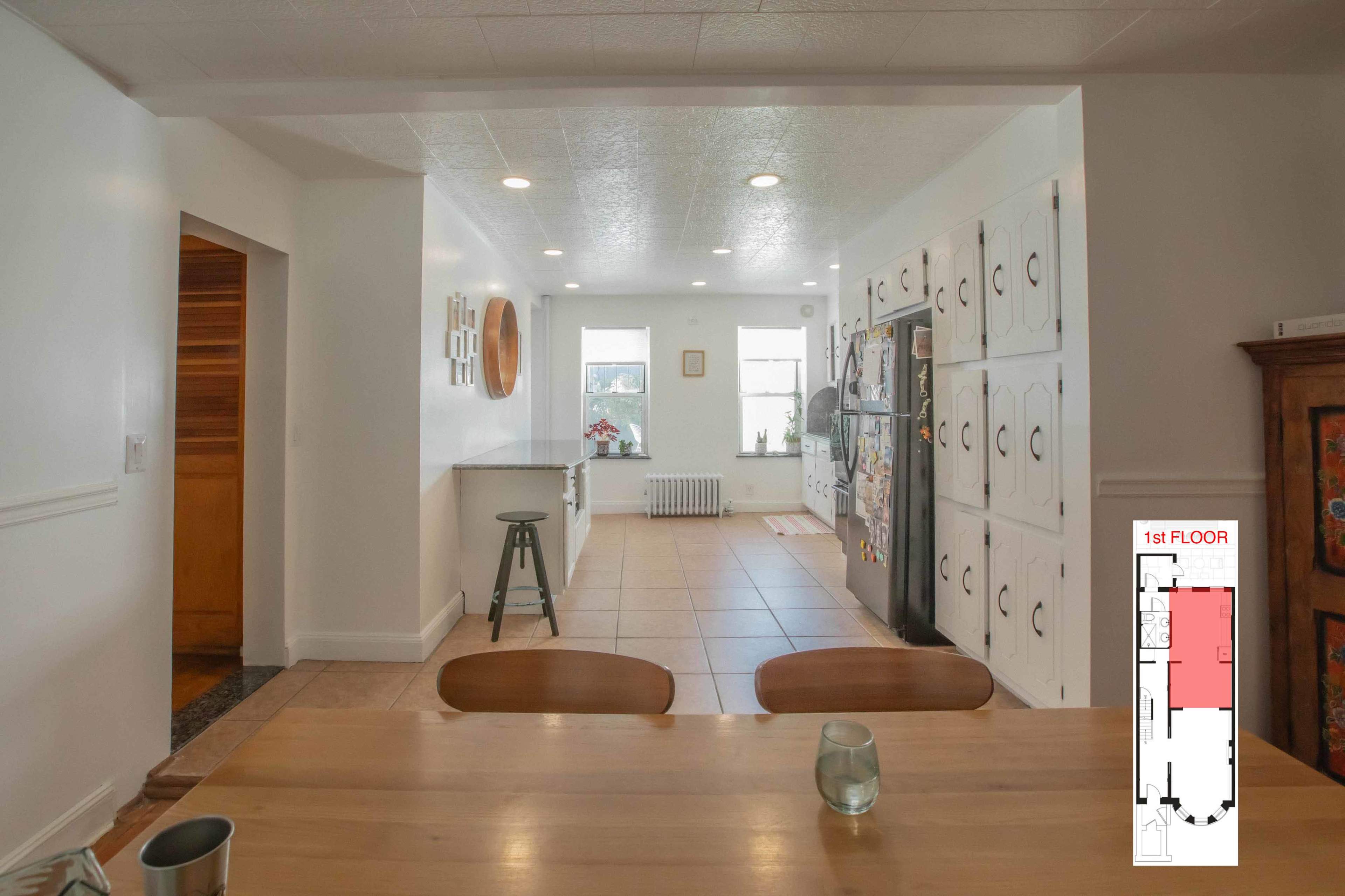 A modern kitchen with a dining table in the foreground, a refrigerator and cabinets along one wall, and a layout map in the bottom right corner.