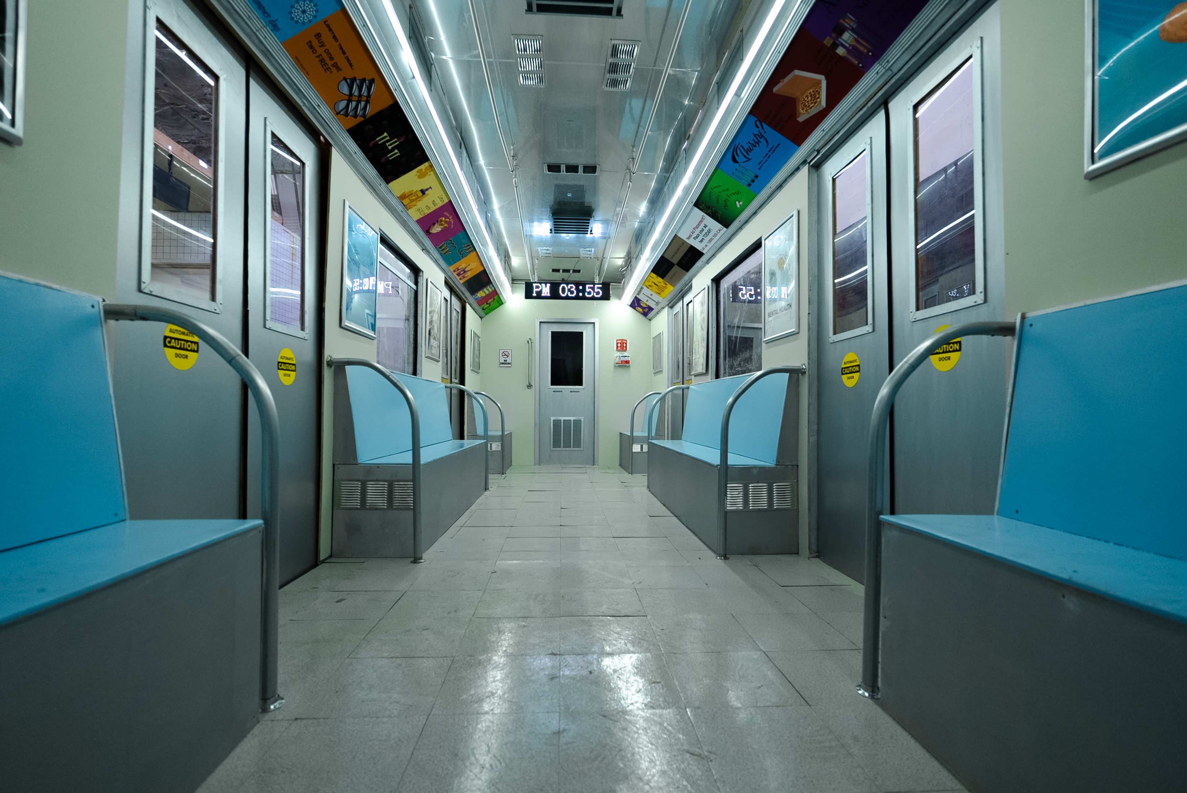 The interior of a subway car features blue benches along the sides and a digital clock displaying the time.