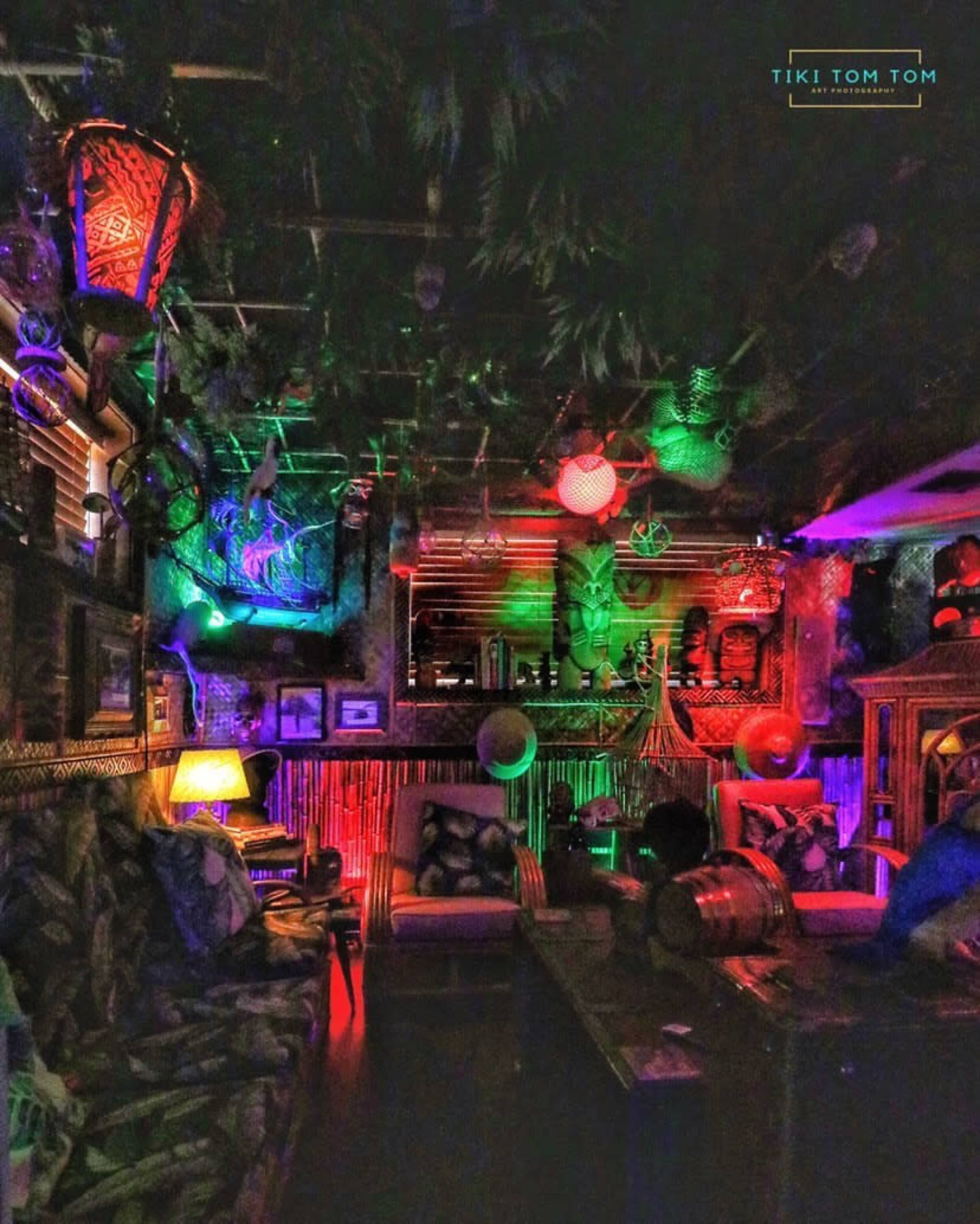A colorful tiki-themed bar interior decorated with lanterns, vibrant lights, and tropical decor.