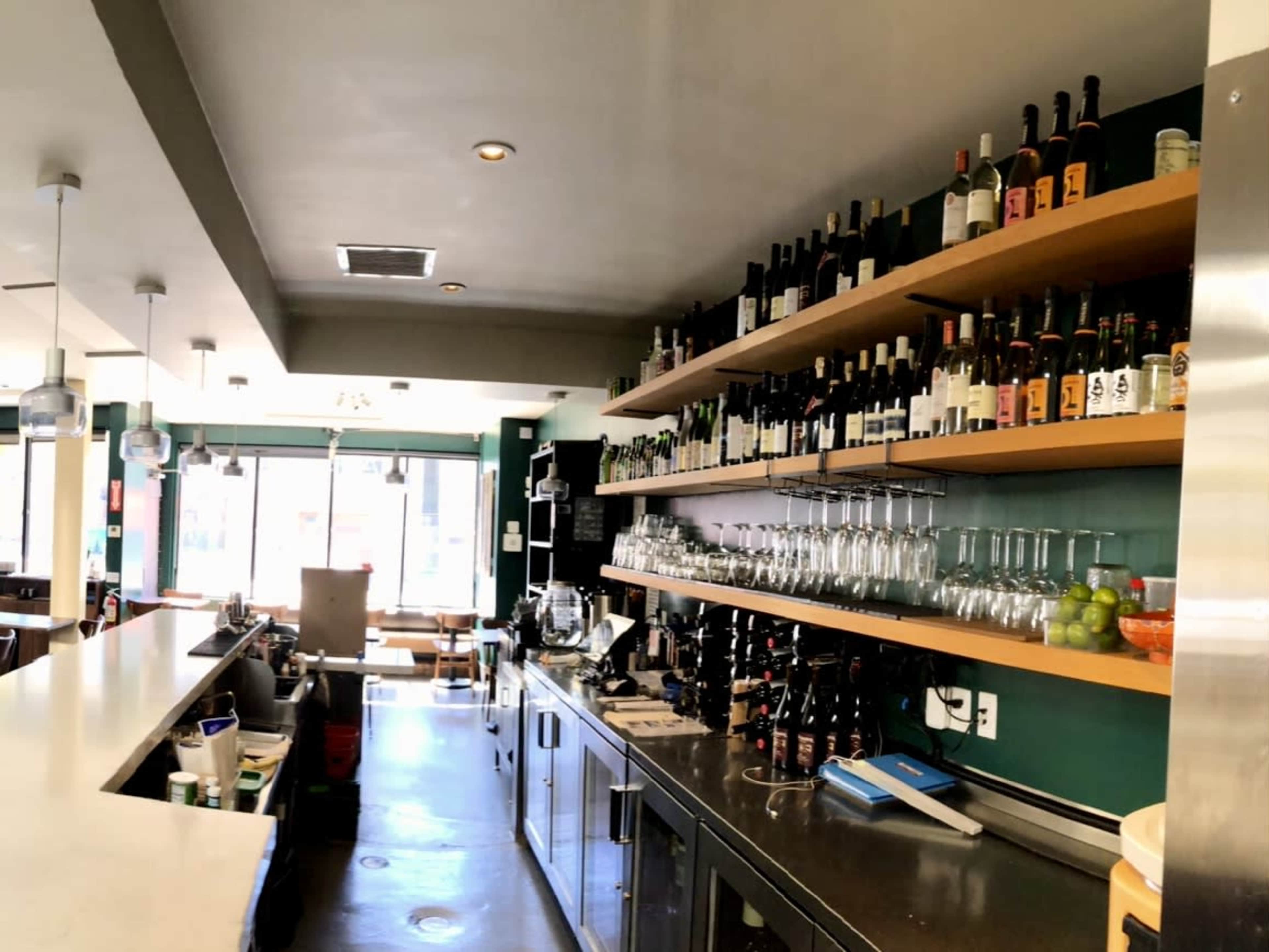 A well-organized bar area features shelves stocked with various bottles and glasses neatly arranged on the counter.