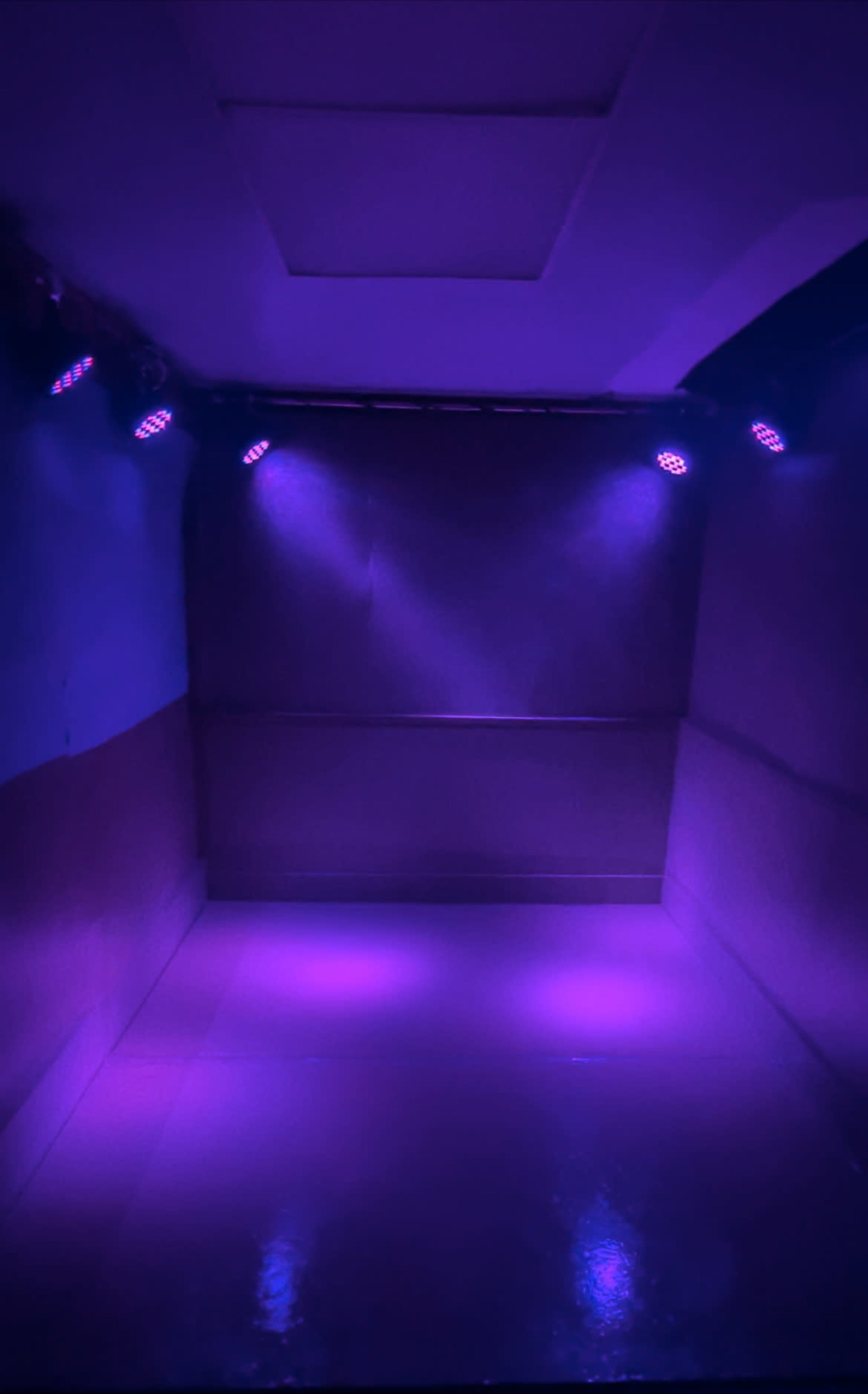 A dimly lit, empty room with purple lights illuminating the walls and floor.