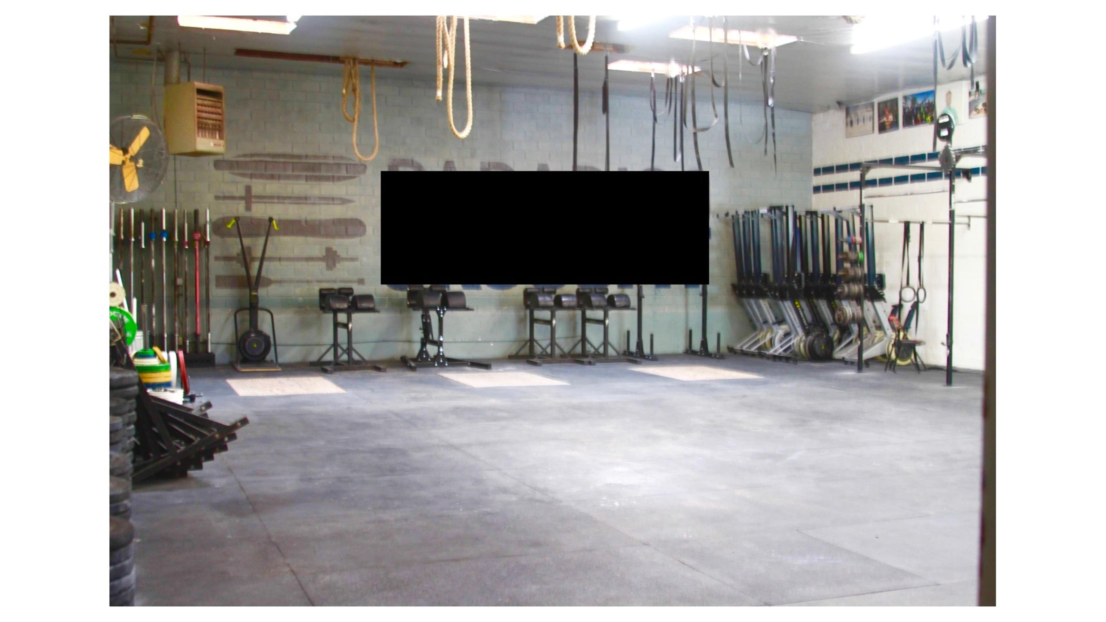 A spacious gym with various exercise equipment lined against the walls and a large open area in the center.