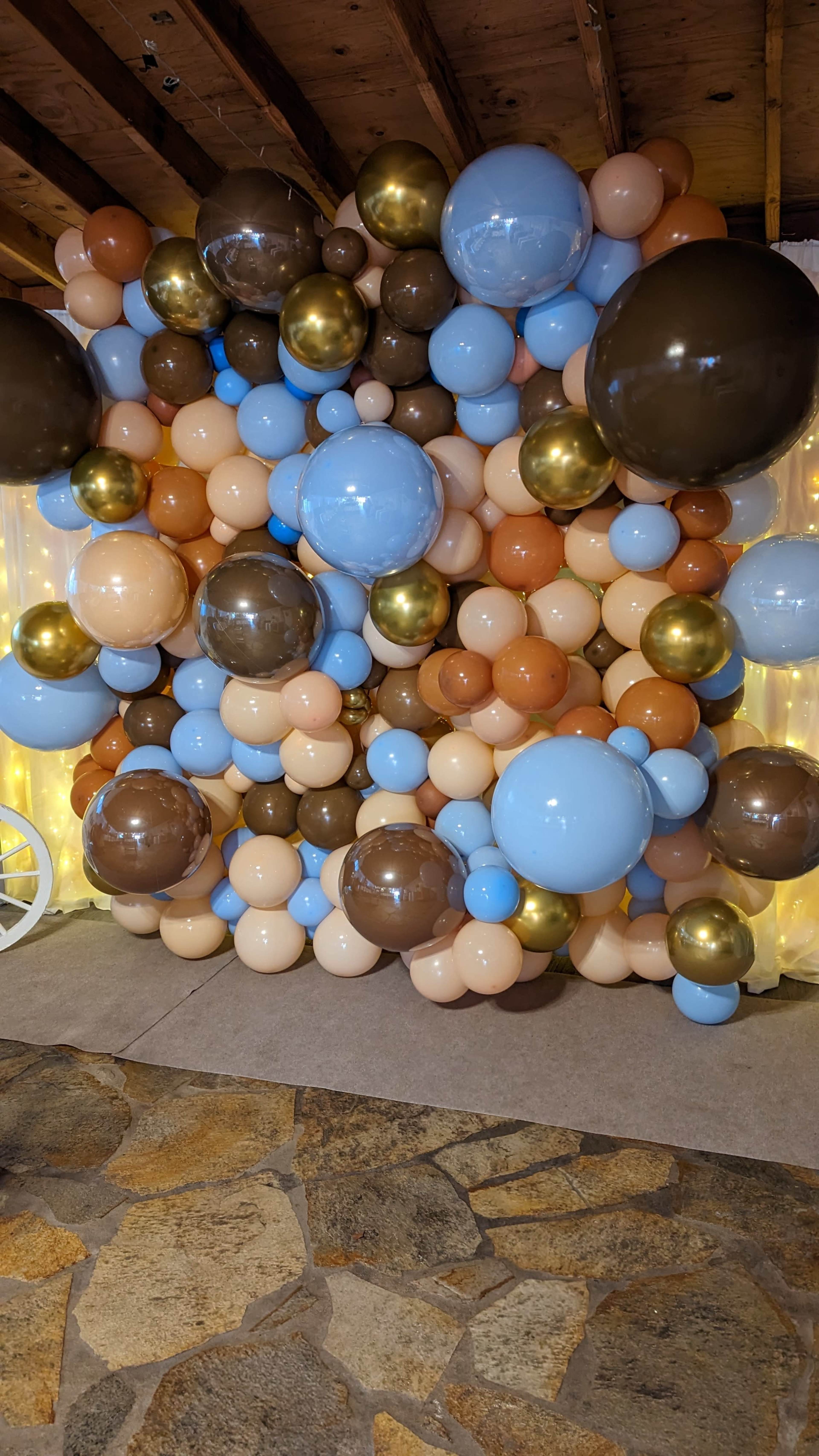 A decorative wall made of various-sized balloons in shades of blue, brown, and peach.