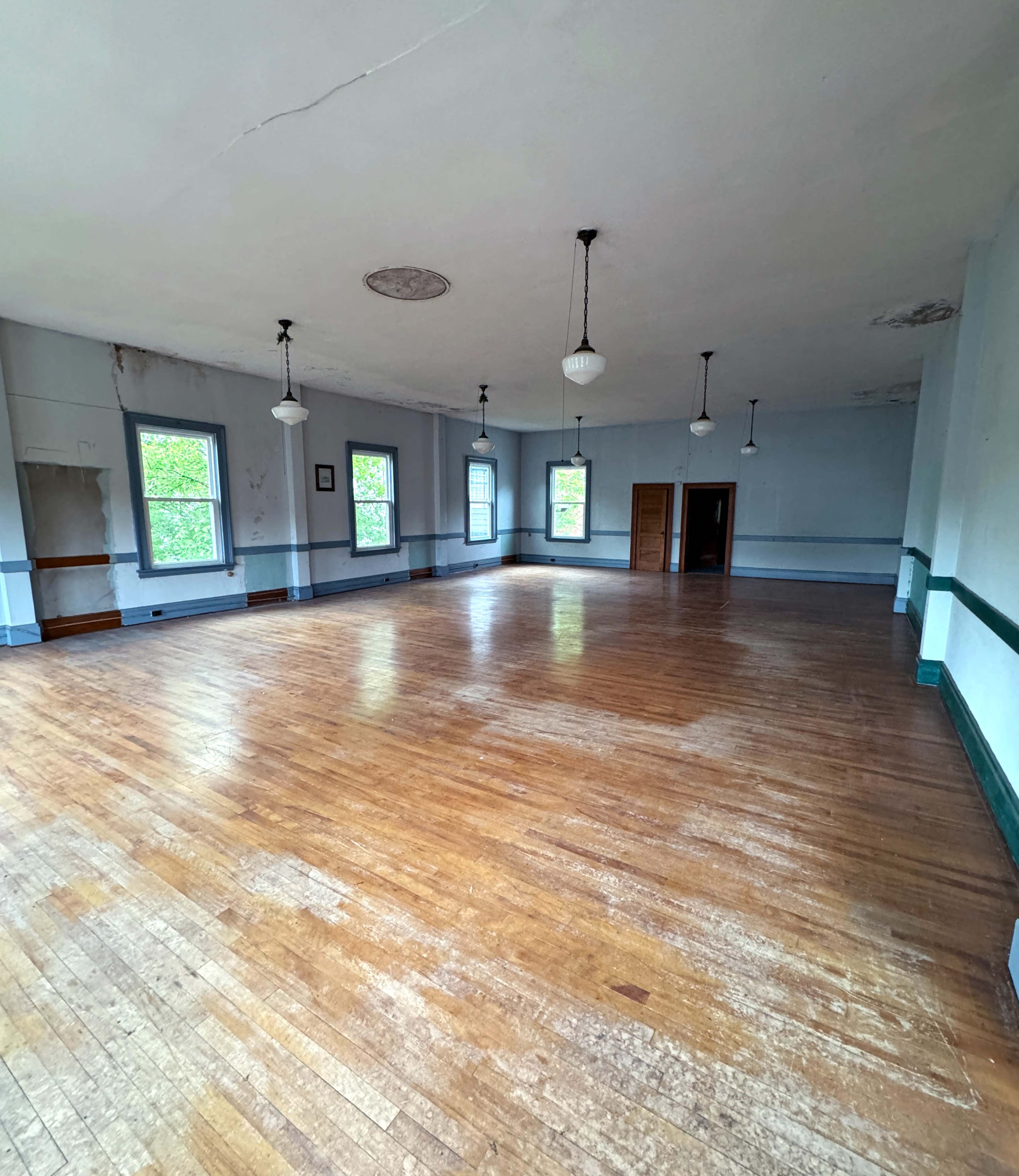 A spacious, empty room with hardwood floors and large windows that create ample natural light.