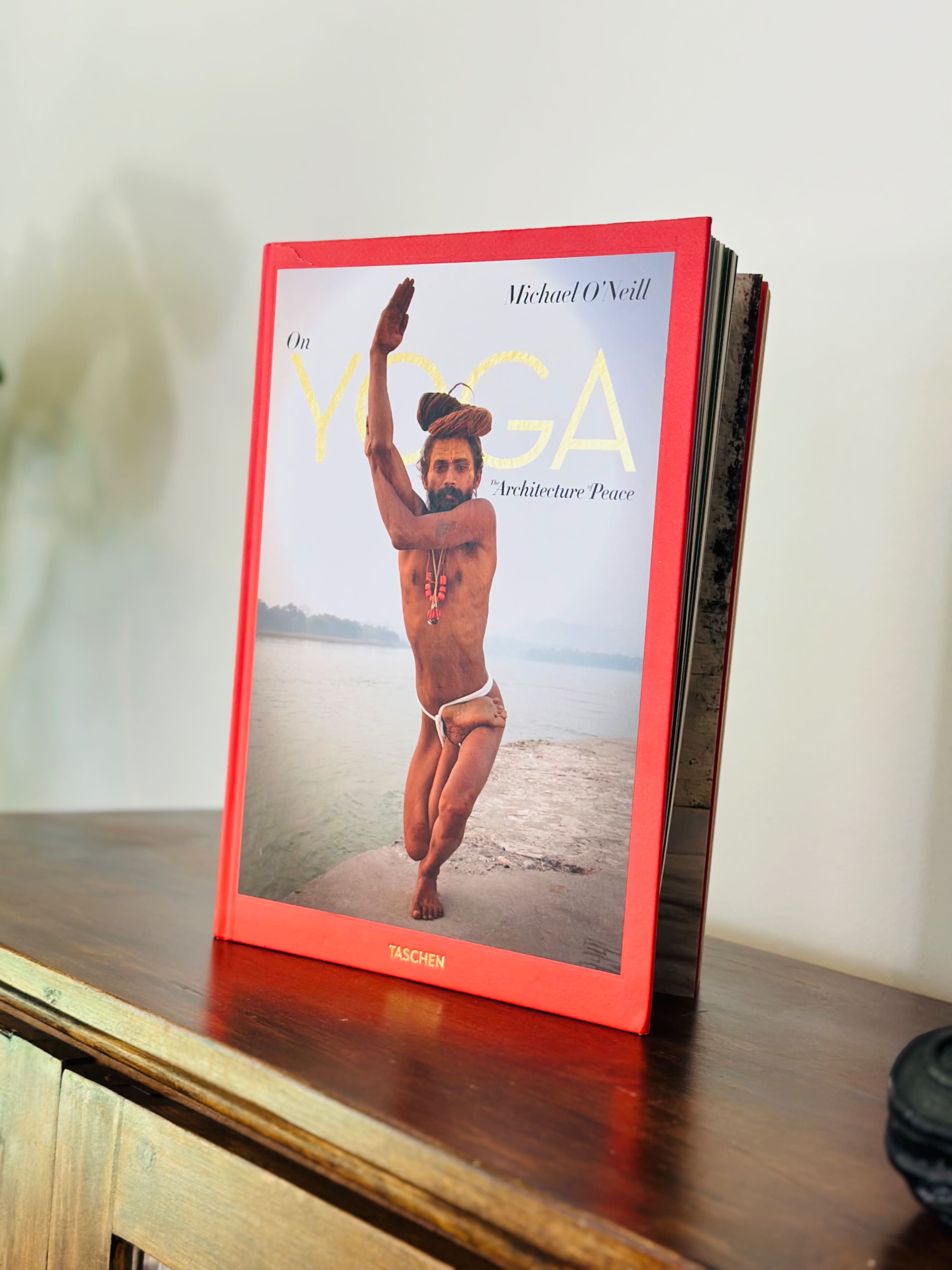 A book titled "On Yoga: The Architecture of Peace" by Michael O'Neill is prominently displayed on a wooden surface.