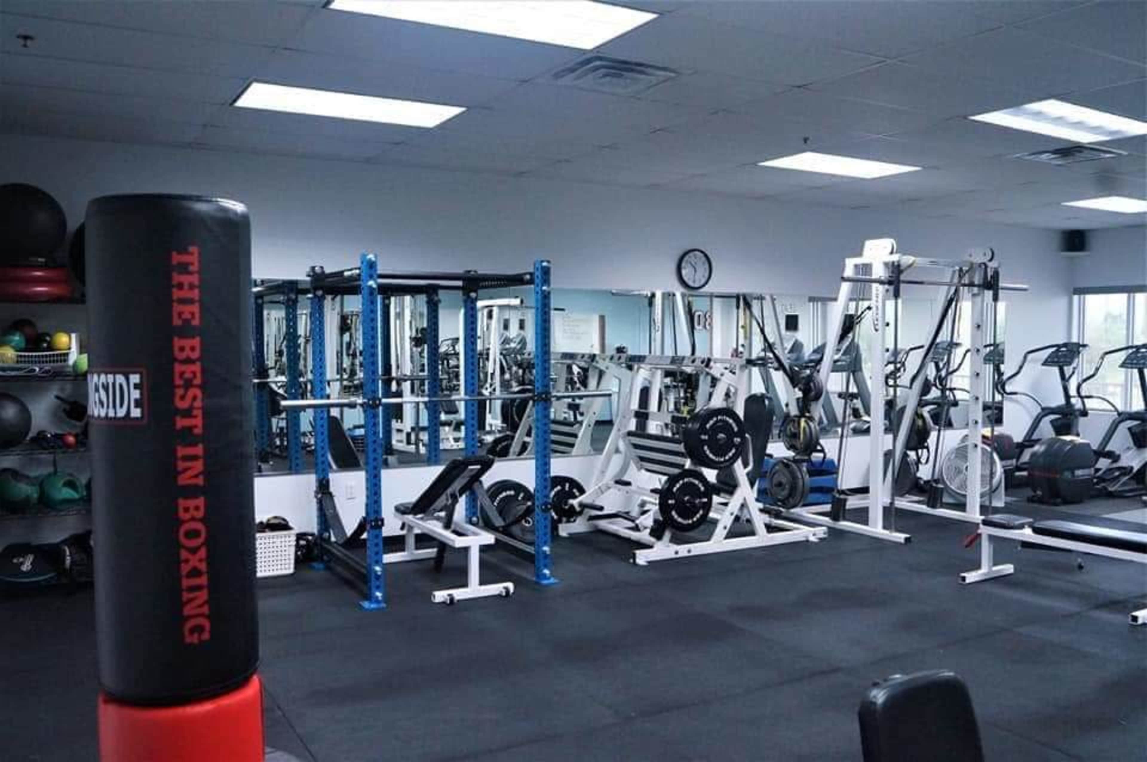 A fitness gym equipped with weightlifting machines, a punching bag, and exercise mats.