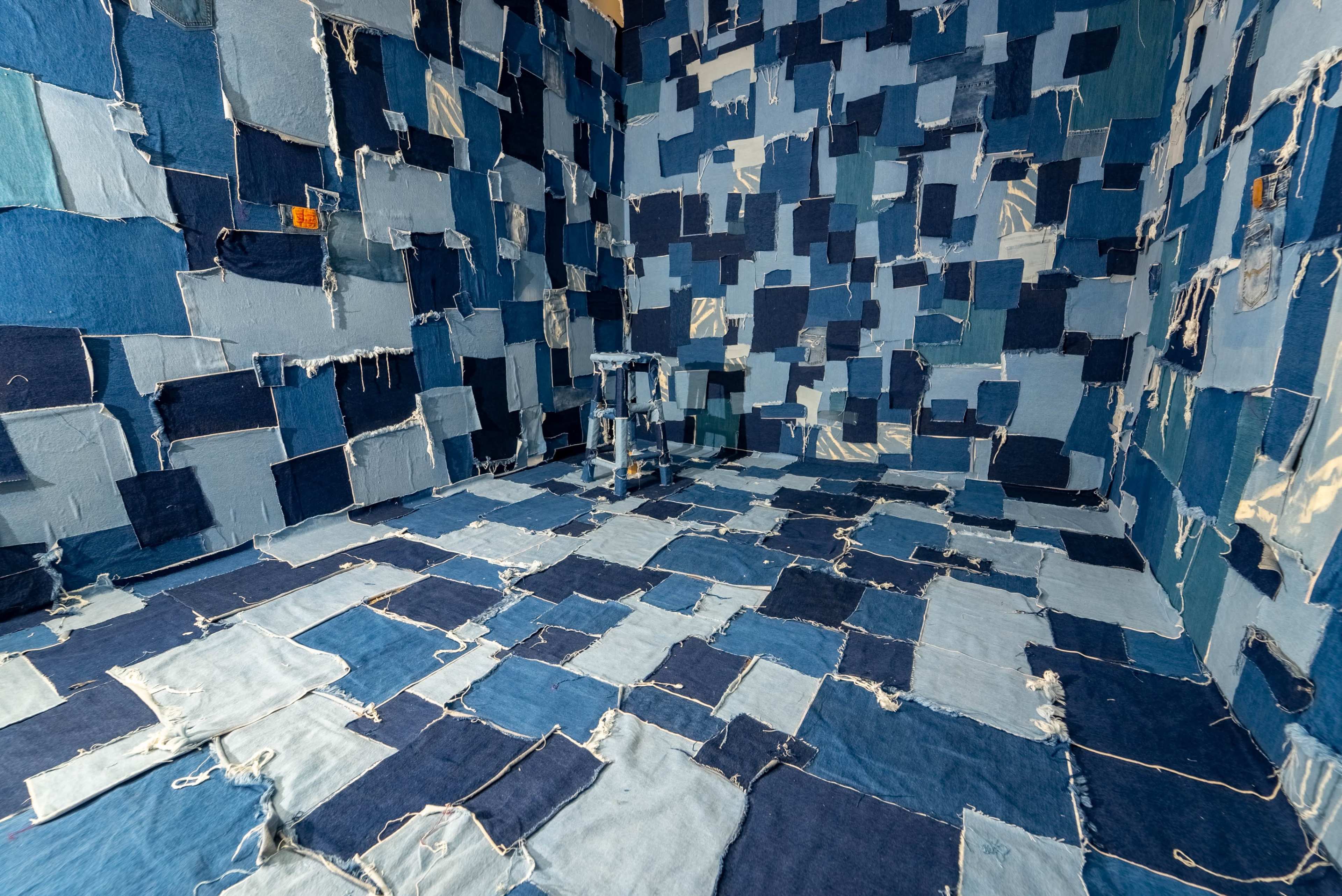 The room is covered with various pieces of blue and denim fabric, creating a patchwork effect on the walls and floor.