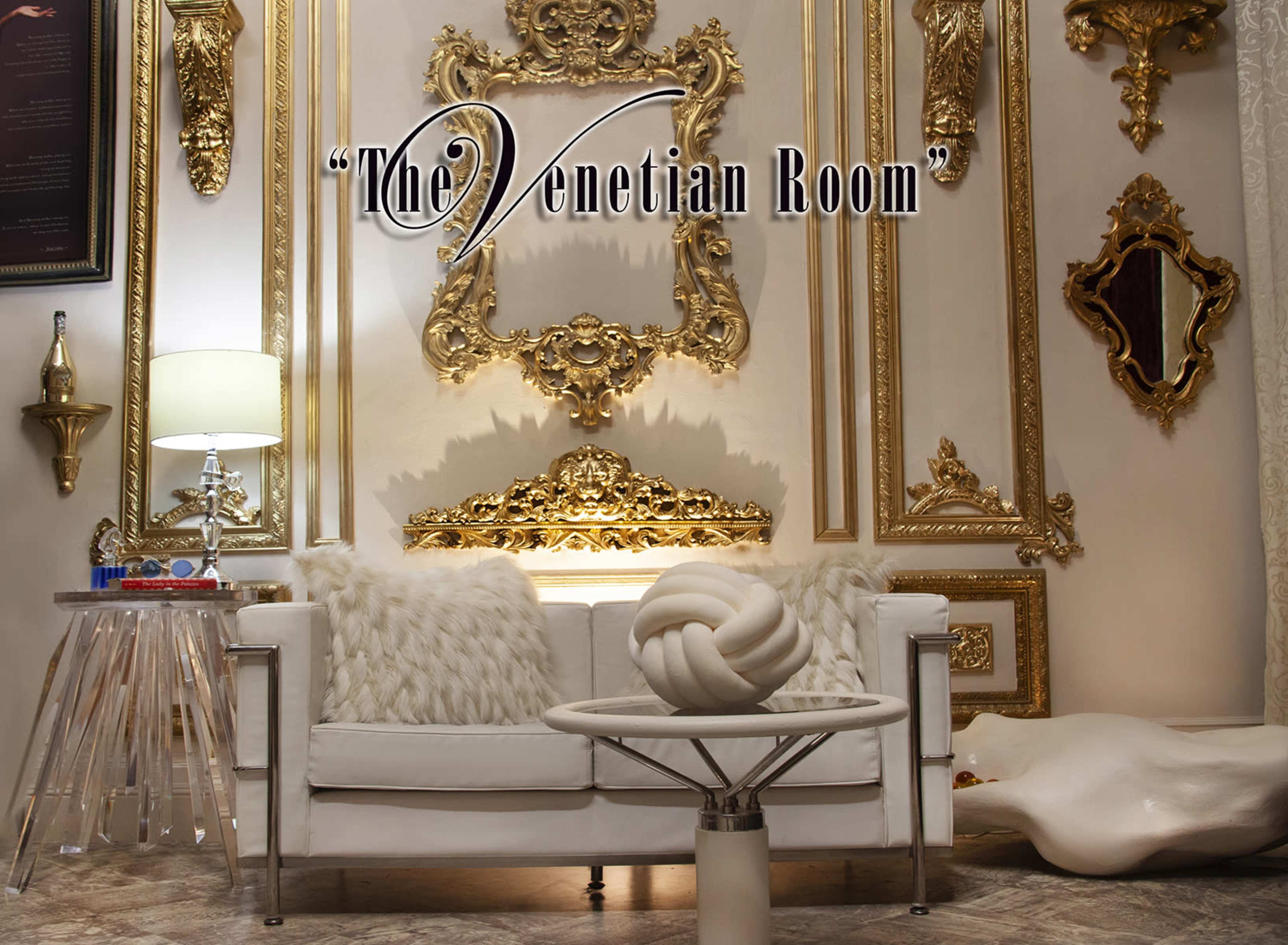 The image shows an elegantly decorated room featuring a white couch, a stylish circular table, and ornate gold-framed wall decorations.