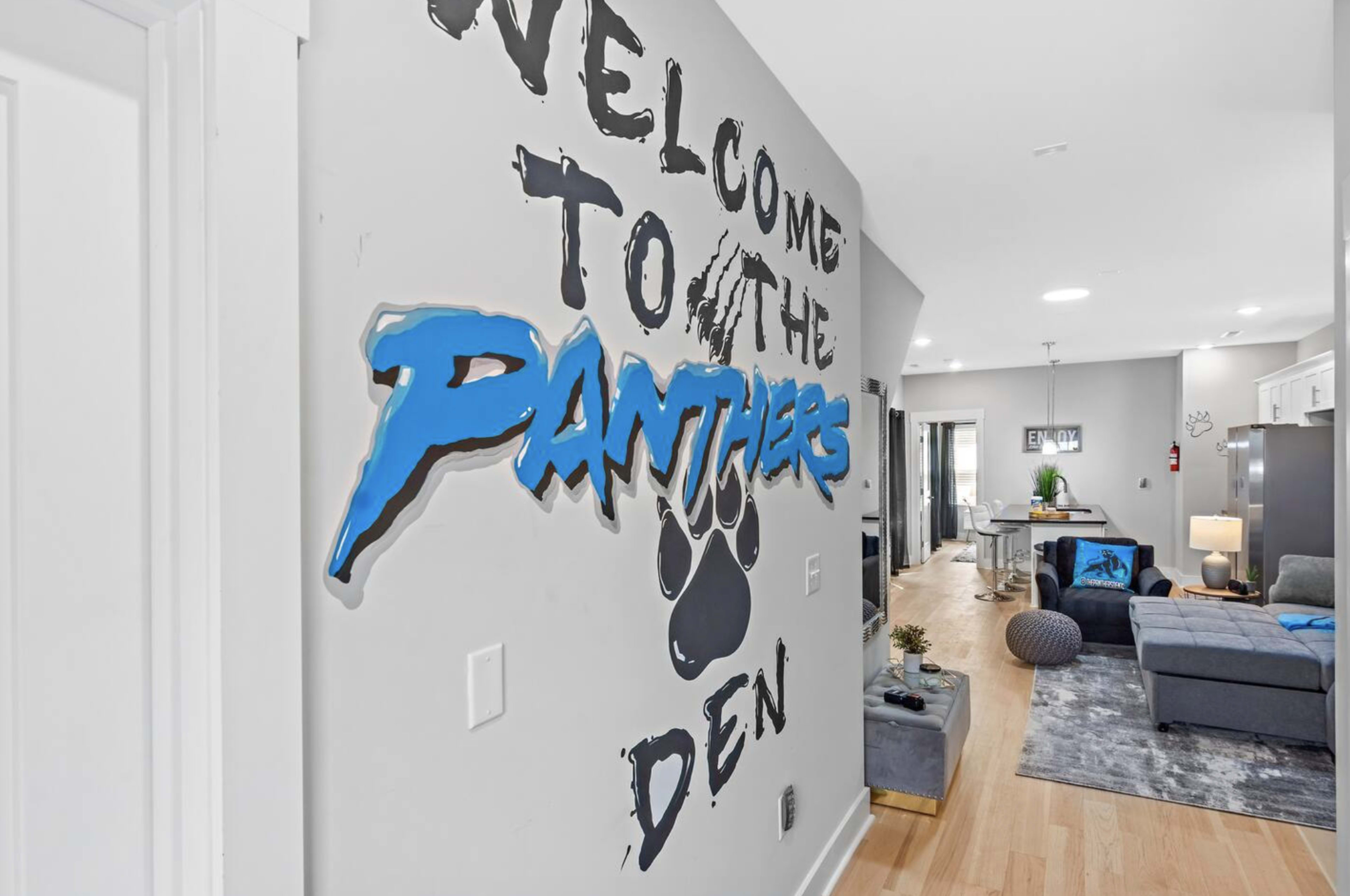 A wall inside a modern room features bold text that reads "Welcome to the Panthers Den" alongside a stylized paw print graphic.