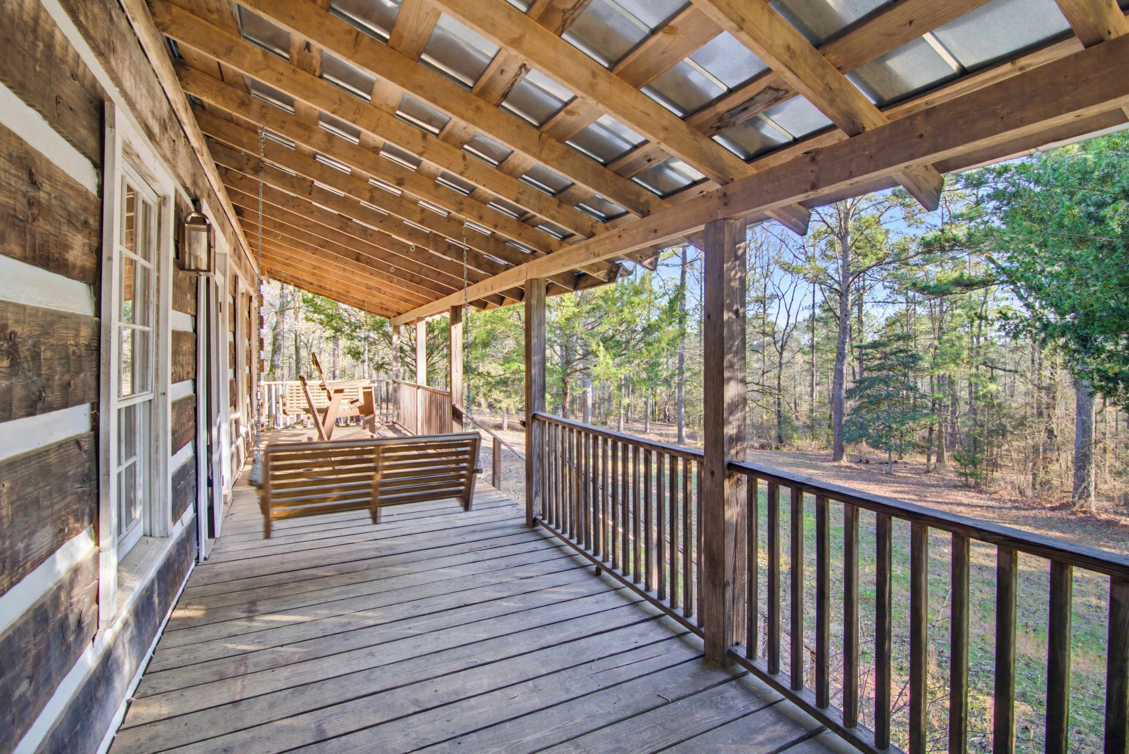 The image shows a wooden porch with a slatted roof, overlooking a forested area.