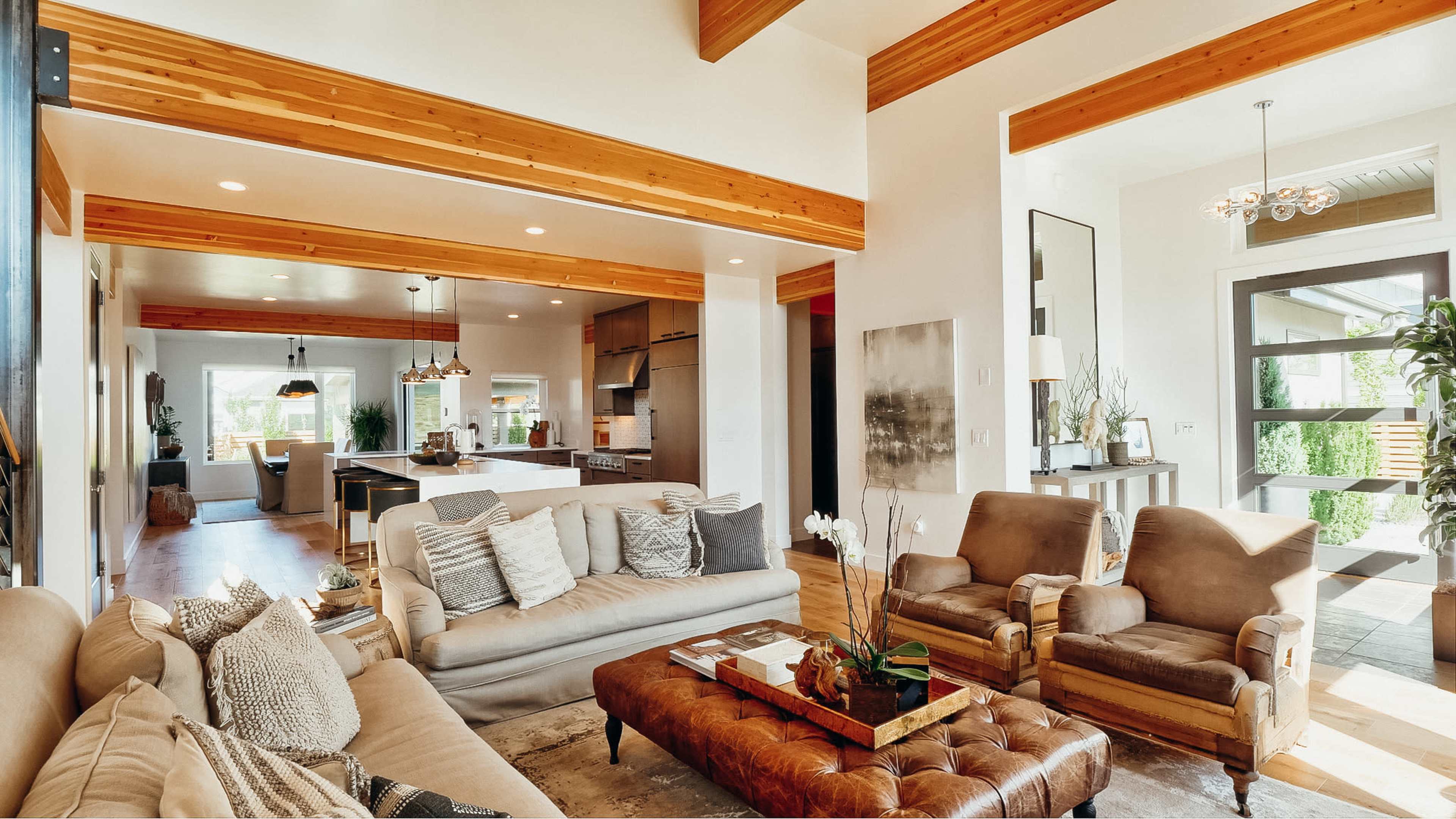 A modern living room featuring two armchairs, a sofa, and a coffee table, with an open layout that connects to a kitchen area in the background.