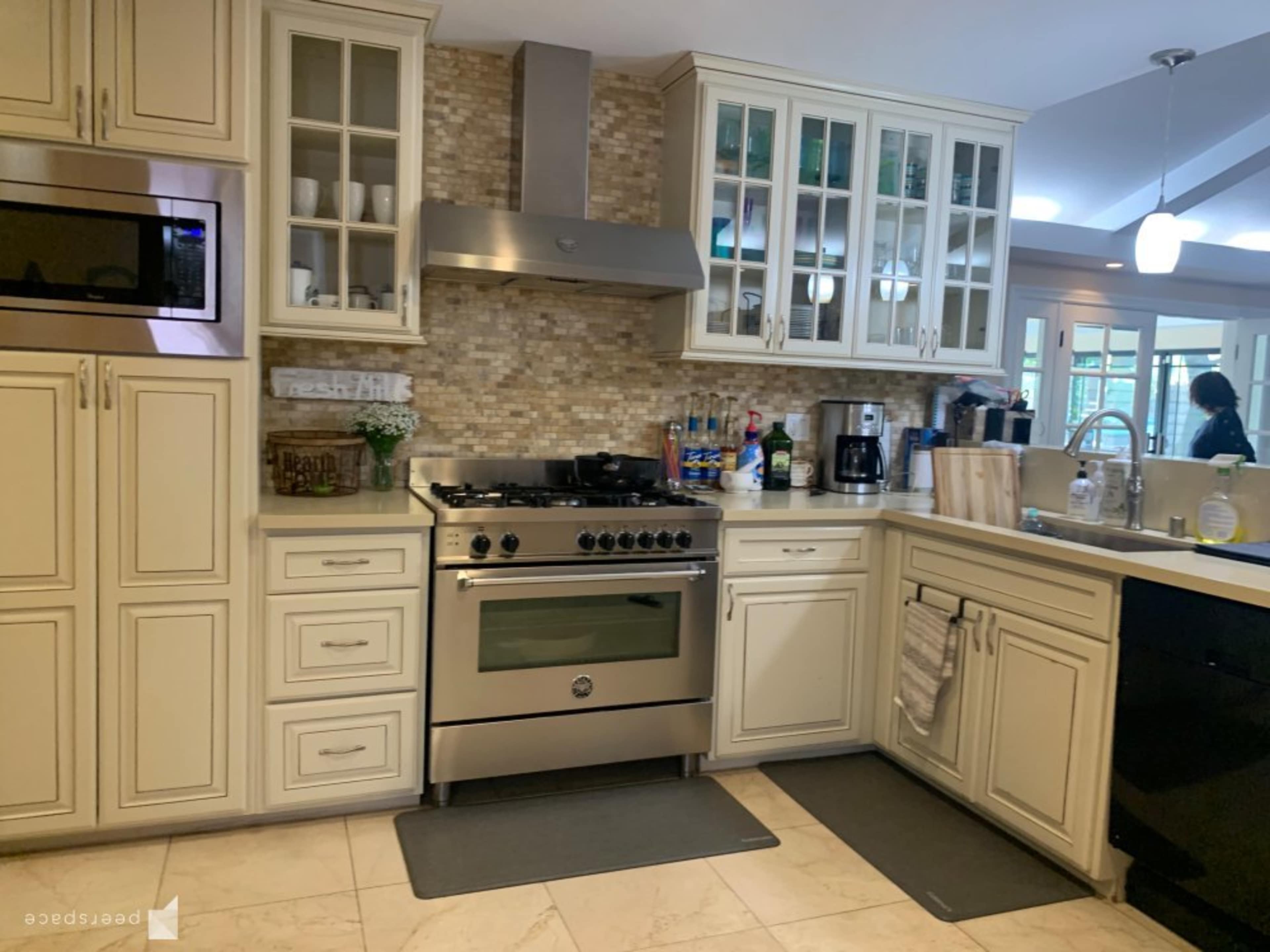 A modern kitchen features stainless steel appliances, cream-colored cabinets, and a tiled backsplash.
