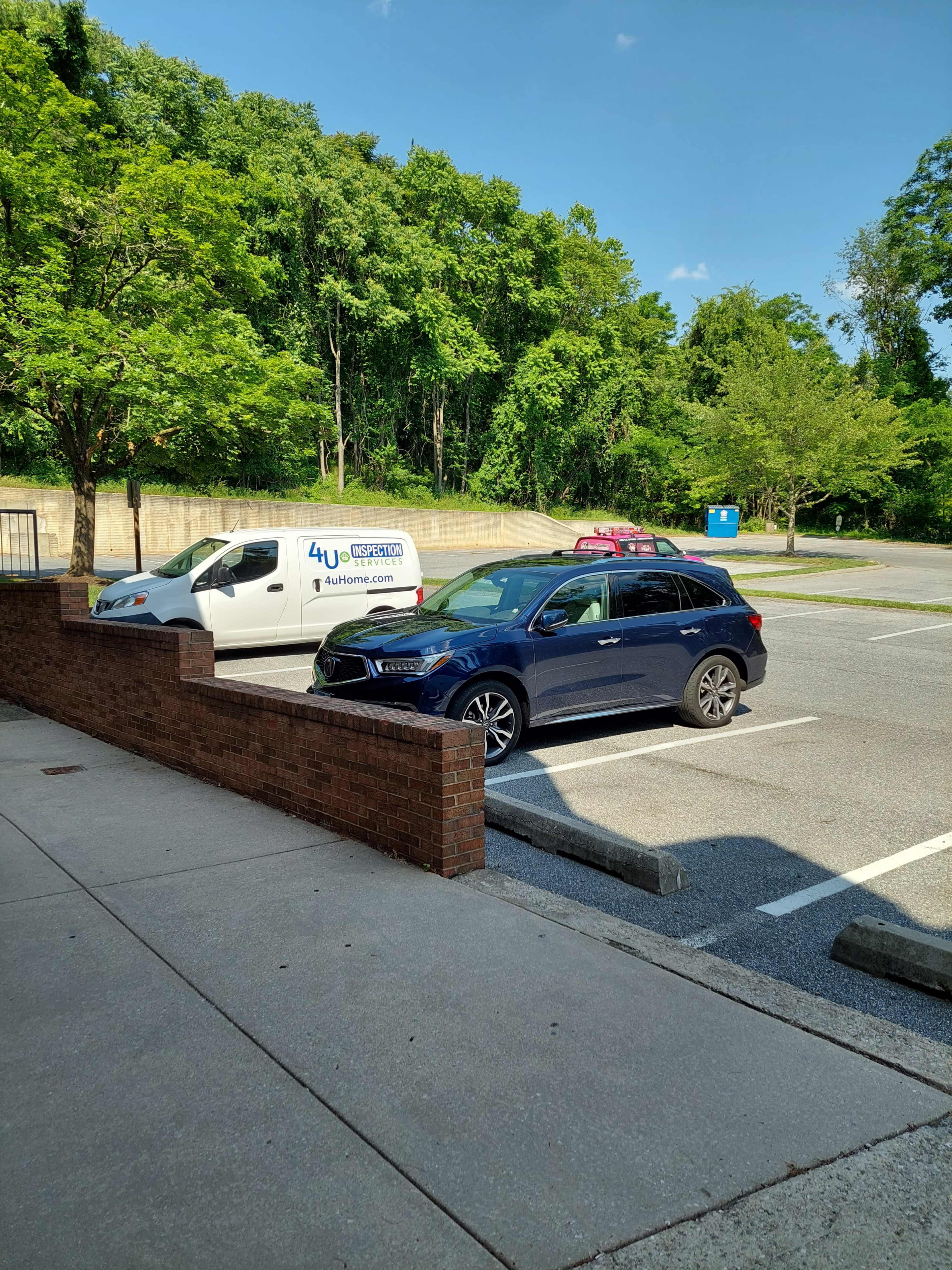 A blue SUV is parked in an empty parking lot beside a white van.