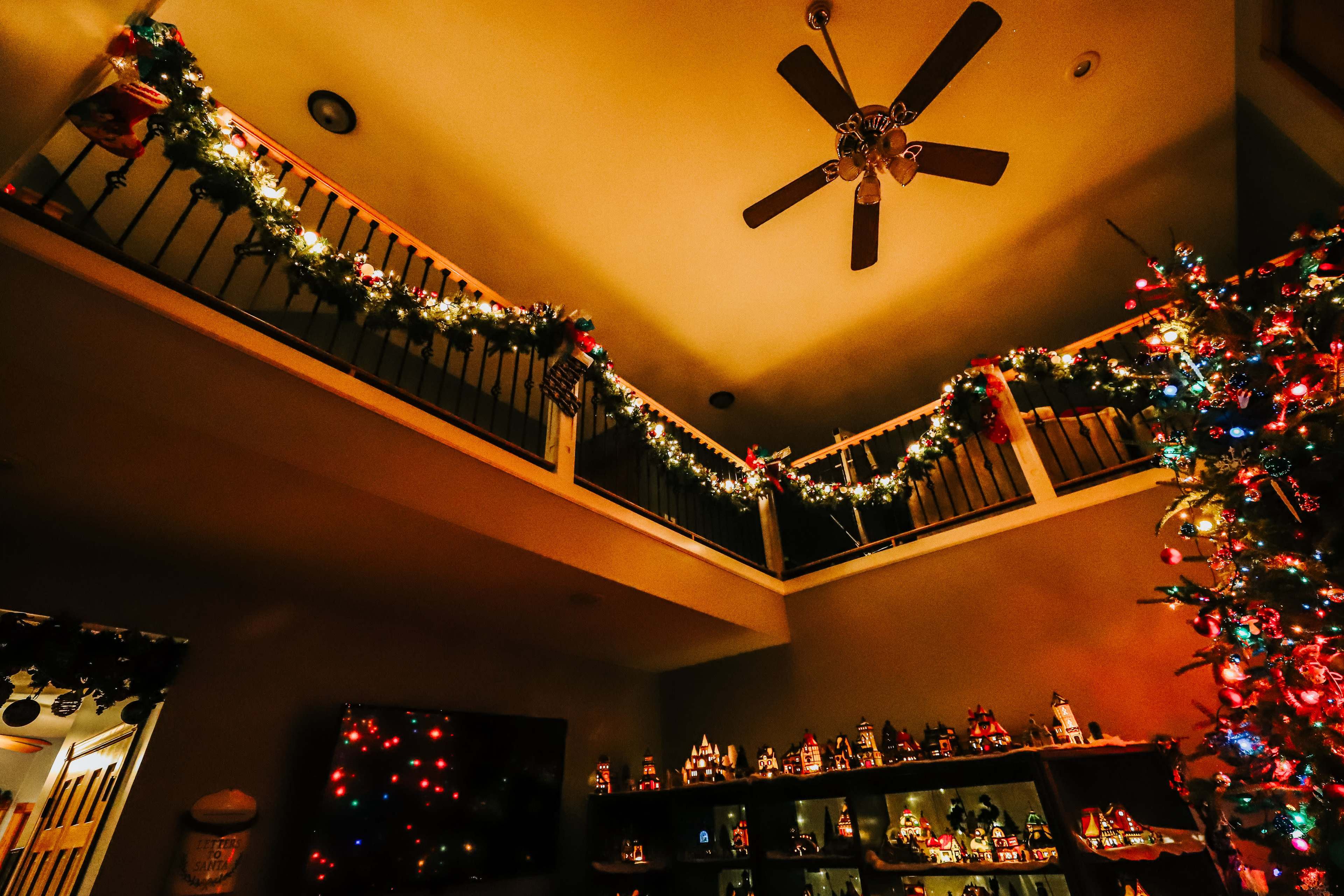 The image shows a festive indoor space decorated with Christmas lights and a tree, along with holiday ornaments displayed on shelves.