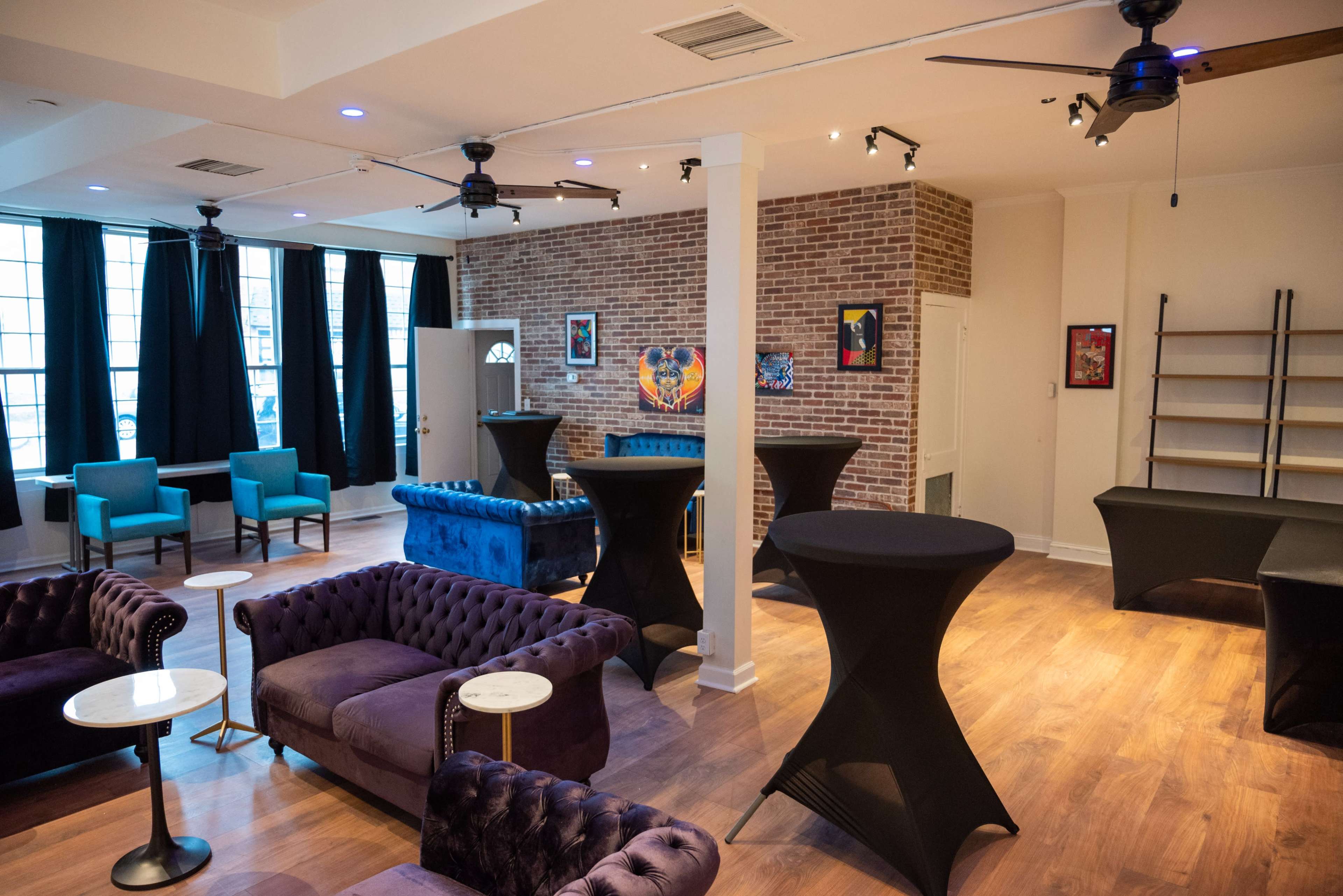 A spacious, modern event space with a mix of plush seating, high tables, and large windows.