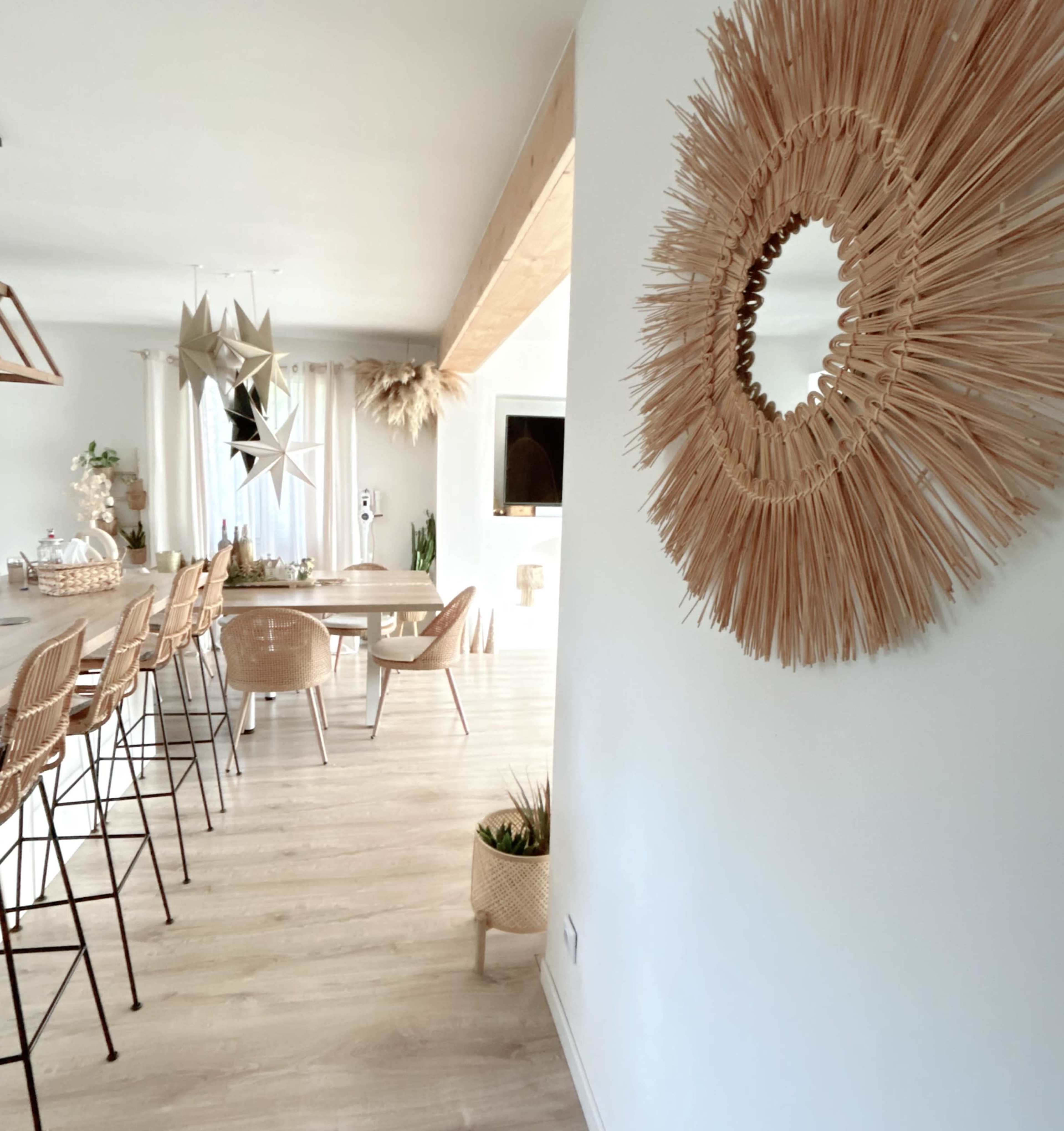 The image shows a stylish, modern interior featuring a dining area with bamboo bar stools and a decorative mirror made of natural materials.