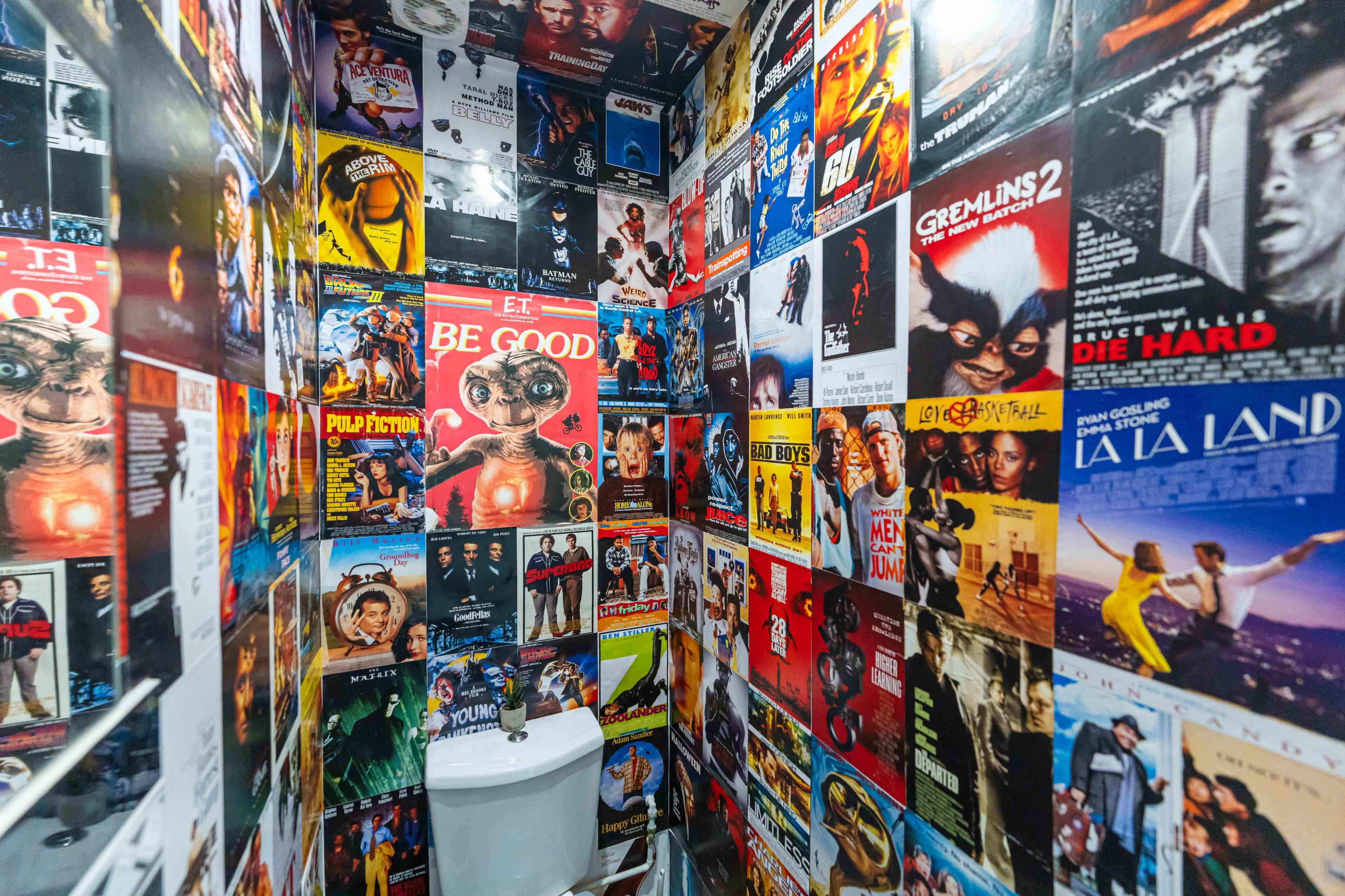 The bathroom is adorned with a collage of movie posters covering the walls.