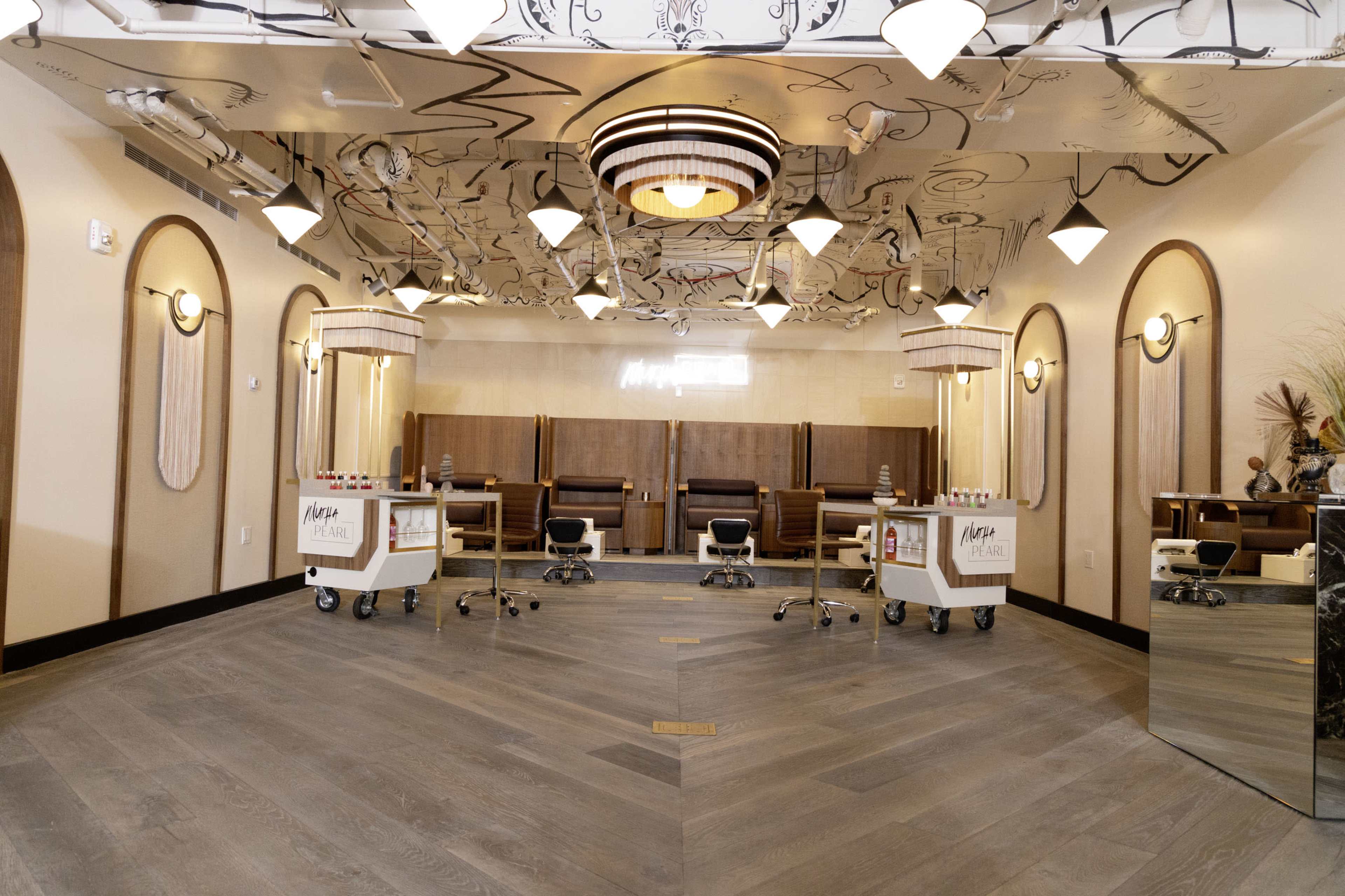 A spacious, modern hair salon with elegant lighting, wooden accents, and styling stations arranged along the walls.
