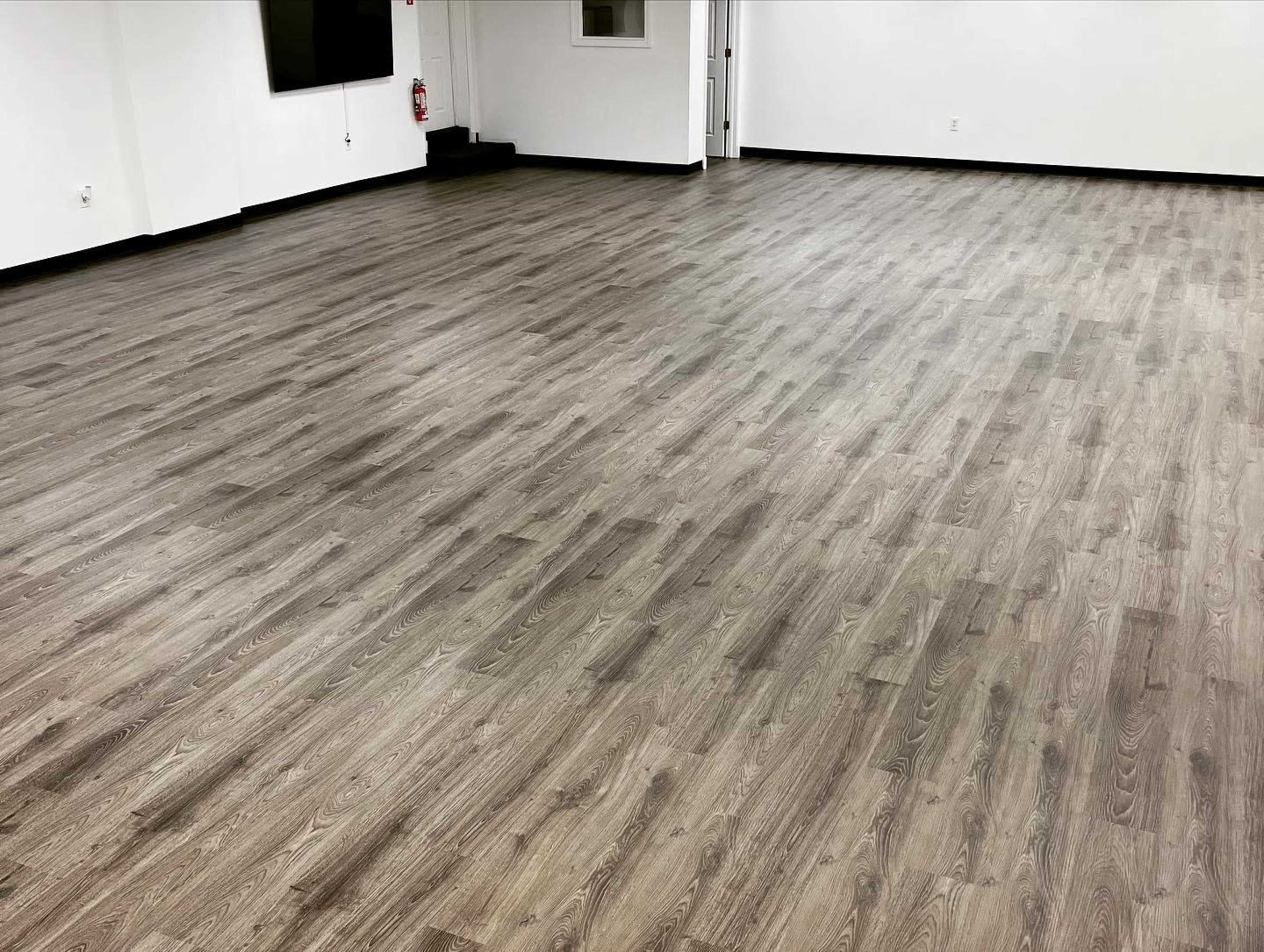 A spacious room with a wooden floor and white walls.