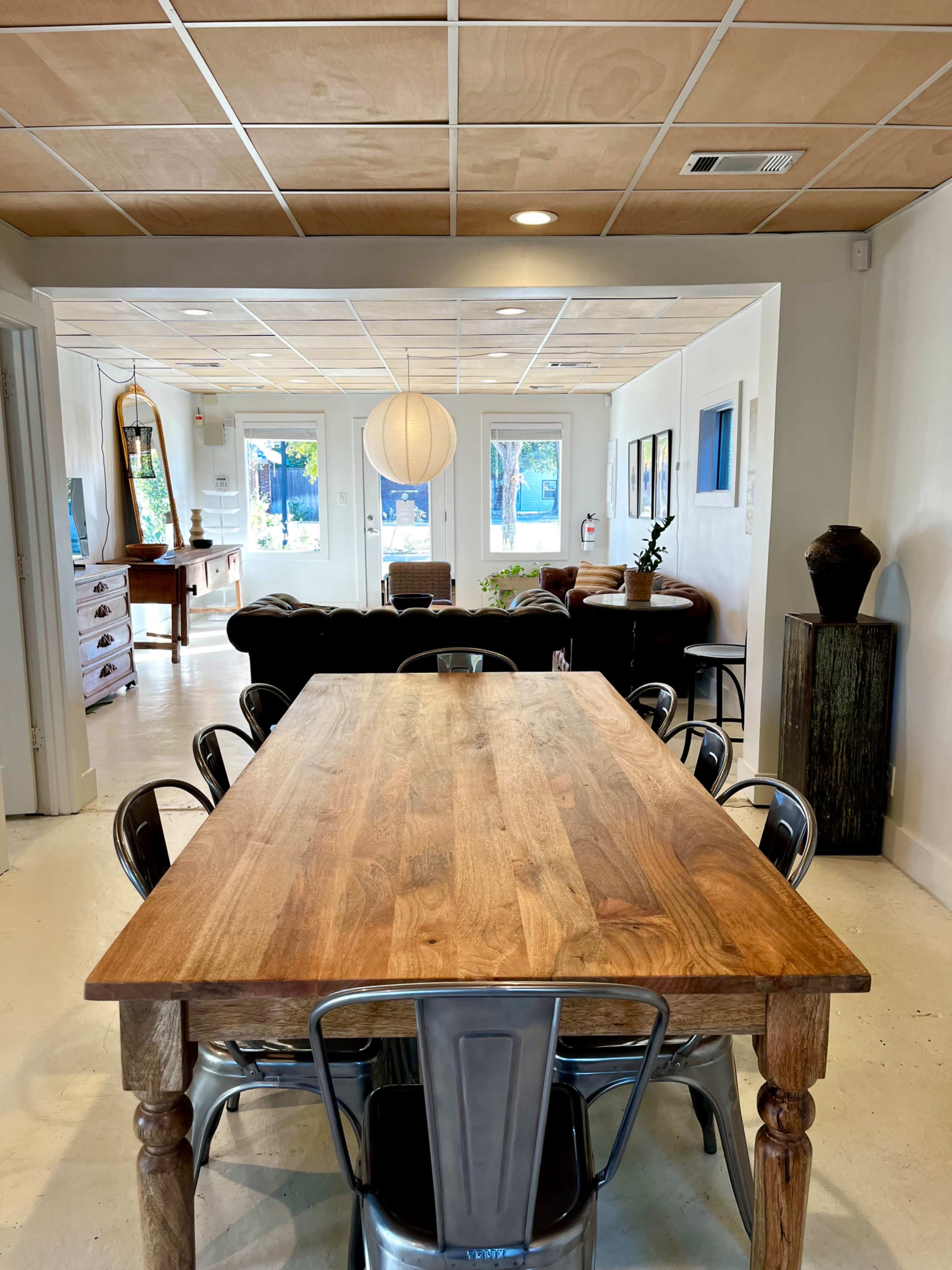 A wooden dining table with metal chairs is positioned in a well-lit, open space that features a modern aesthetic.