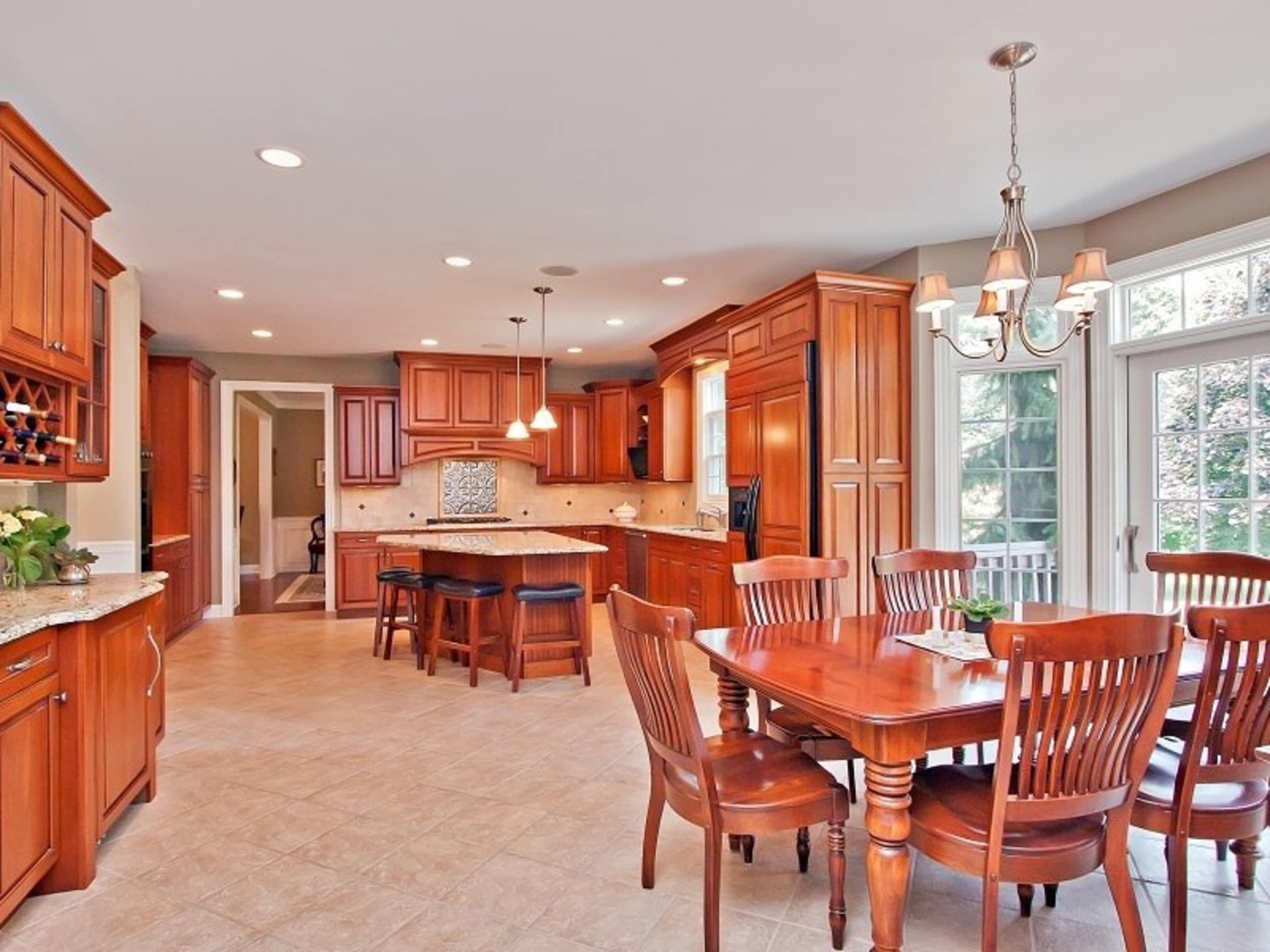 A spacious kitchen features wooden cabinetry, a central island, and a dining table with matching chairs.
