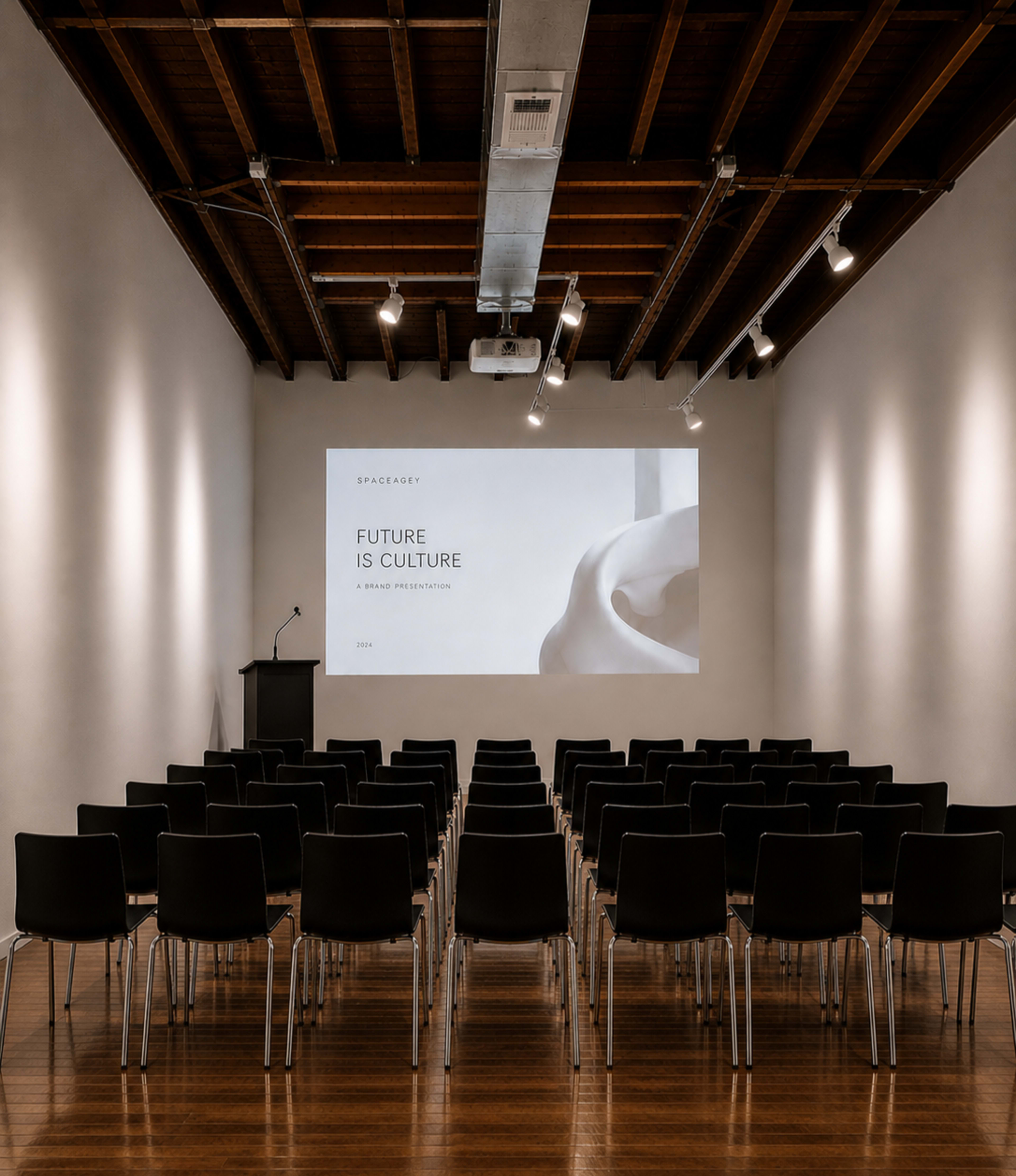 A modern presentation space with rows of black chairs facing a large screen that displays the words "FUTURE IS CULTURE."