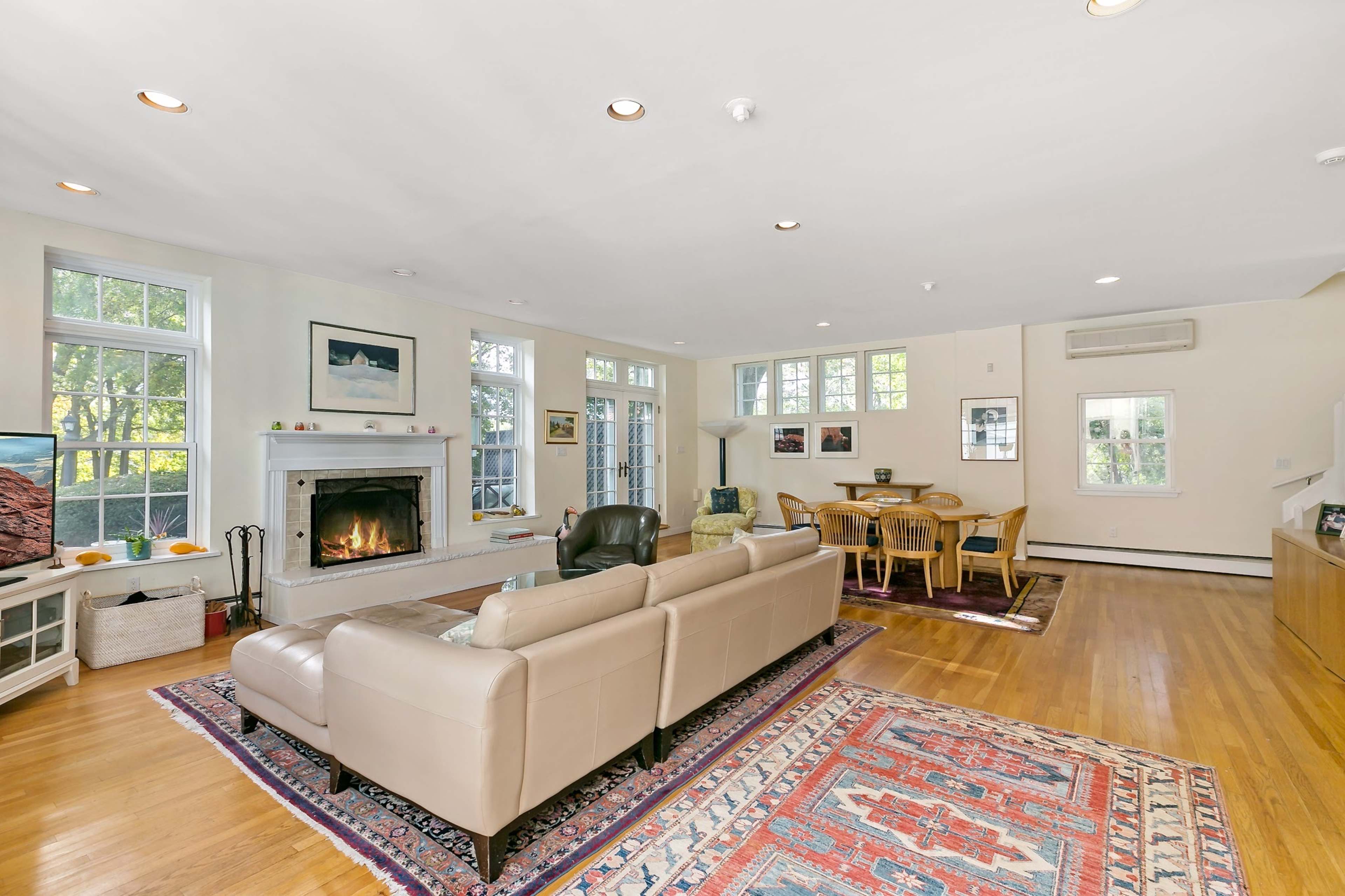 A spacious living room with large windows, a fireplace, and a dining area.